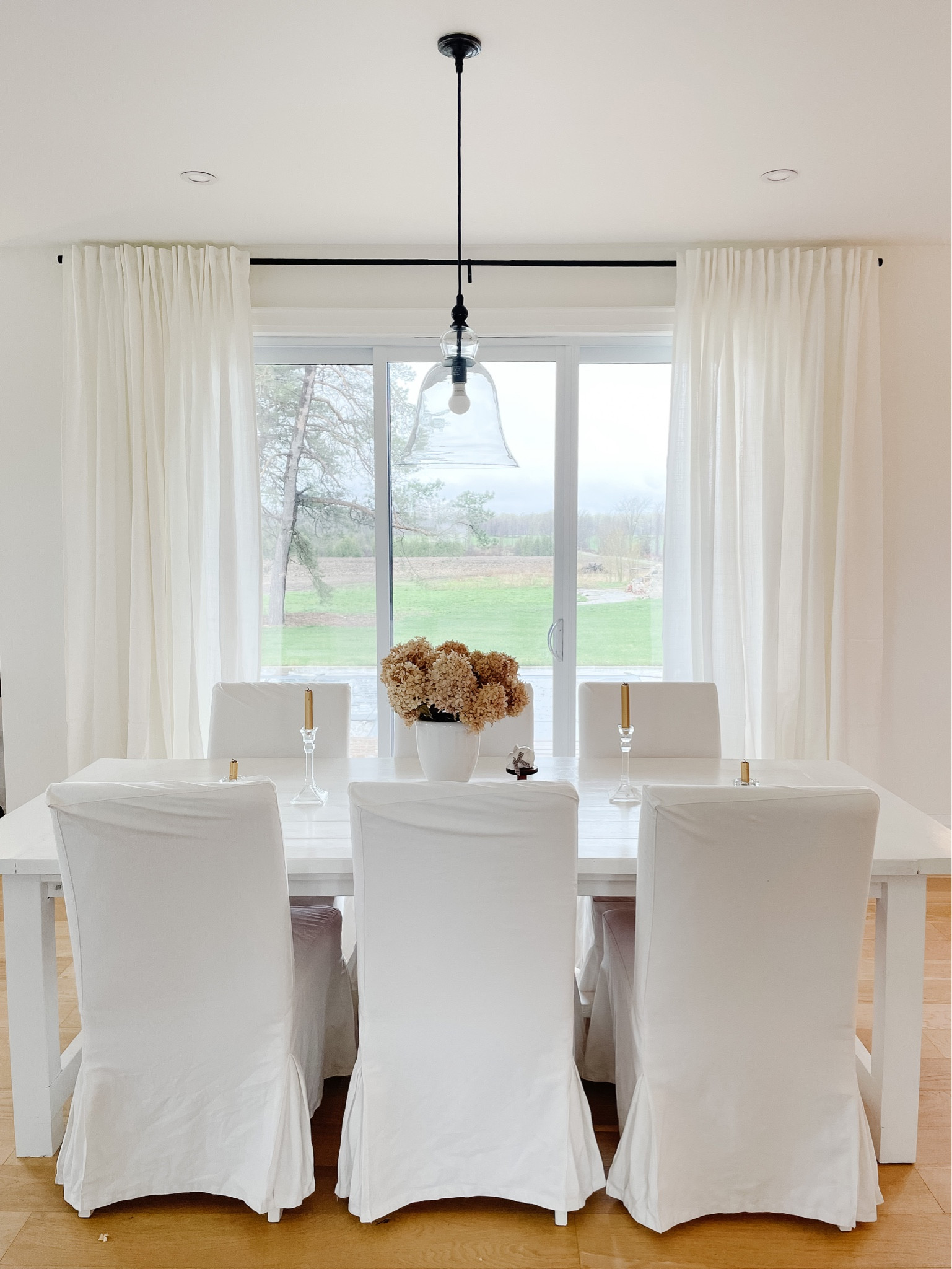 DINING ROOM LOVE 
.
Add in layers and texture with an all white dining room. 
Curtains / painted wood harvest table / fabric slipcover chairs / florals 
And allow the outdoors become the painting! 

#LTKhome #LTKFind