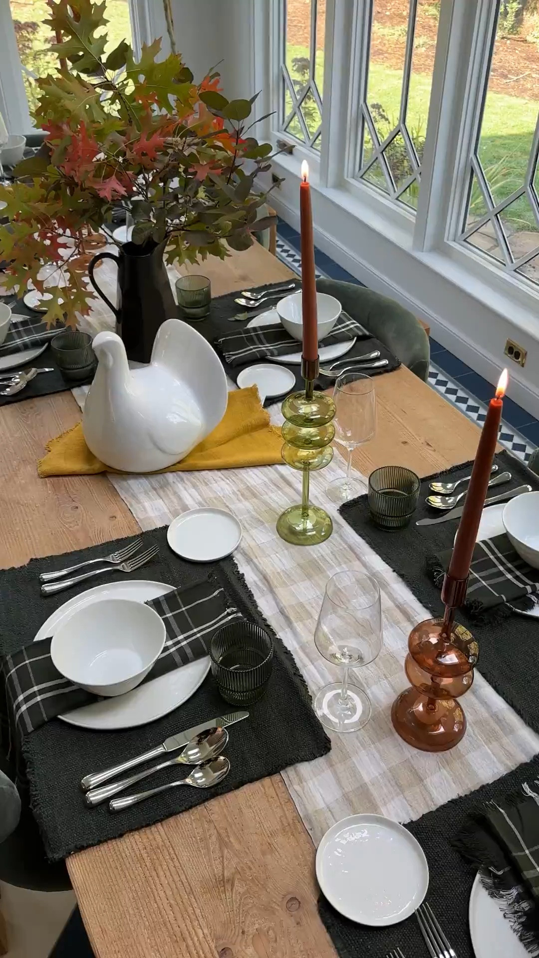As you can see, we have some fall motifs (all from Crate & Barrel) – the plaid runner, the amber candle holders (and candlesticks), one mustard napkin, some fall leaves and you know, THE HUGE CERAMIC TURKEY. But beyond that, it’s just white plates, with green napkins, glassware, and pretty silver flatware. All these things work year-round in my house (which leans green/blue modern farmhouse).

I think it’s fun to think of some of these colors, patterns, and elements as “seasonal indicators”. Fall branches + mustard + a warm plaid + Turkey = Thanksgiving. Some scattered pine cones or wicker/wood elements for turkey day and you get the same “vibe”. #cratepartner

#LTKHome #LTKSeasonal #LTKParties