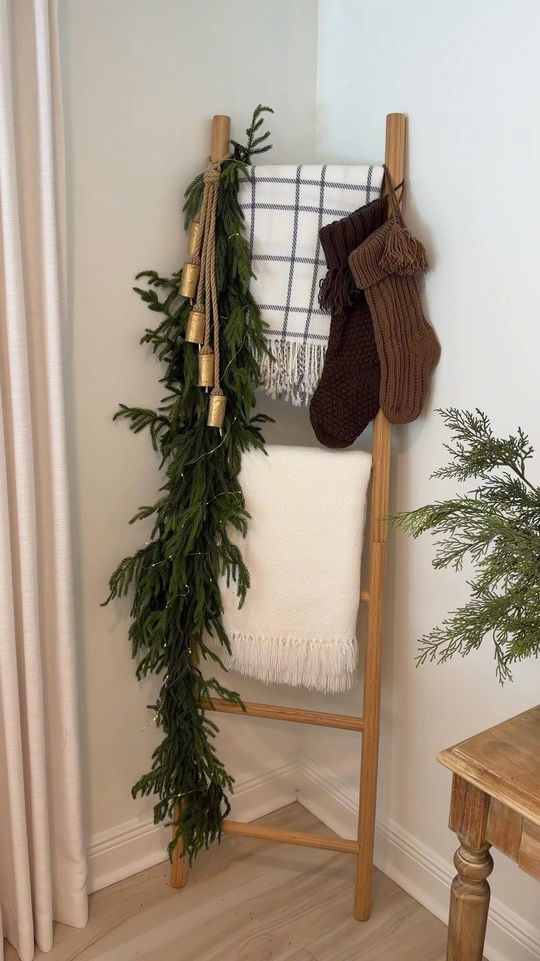 How to decorate your ladder for Christmas! This is an easy idea for your living room corner! Greenery garland, throw blankets, bells and stockings!