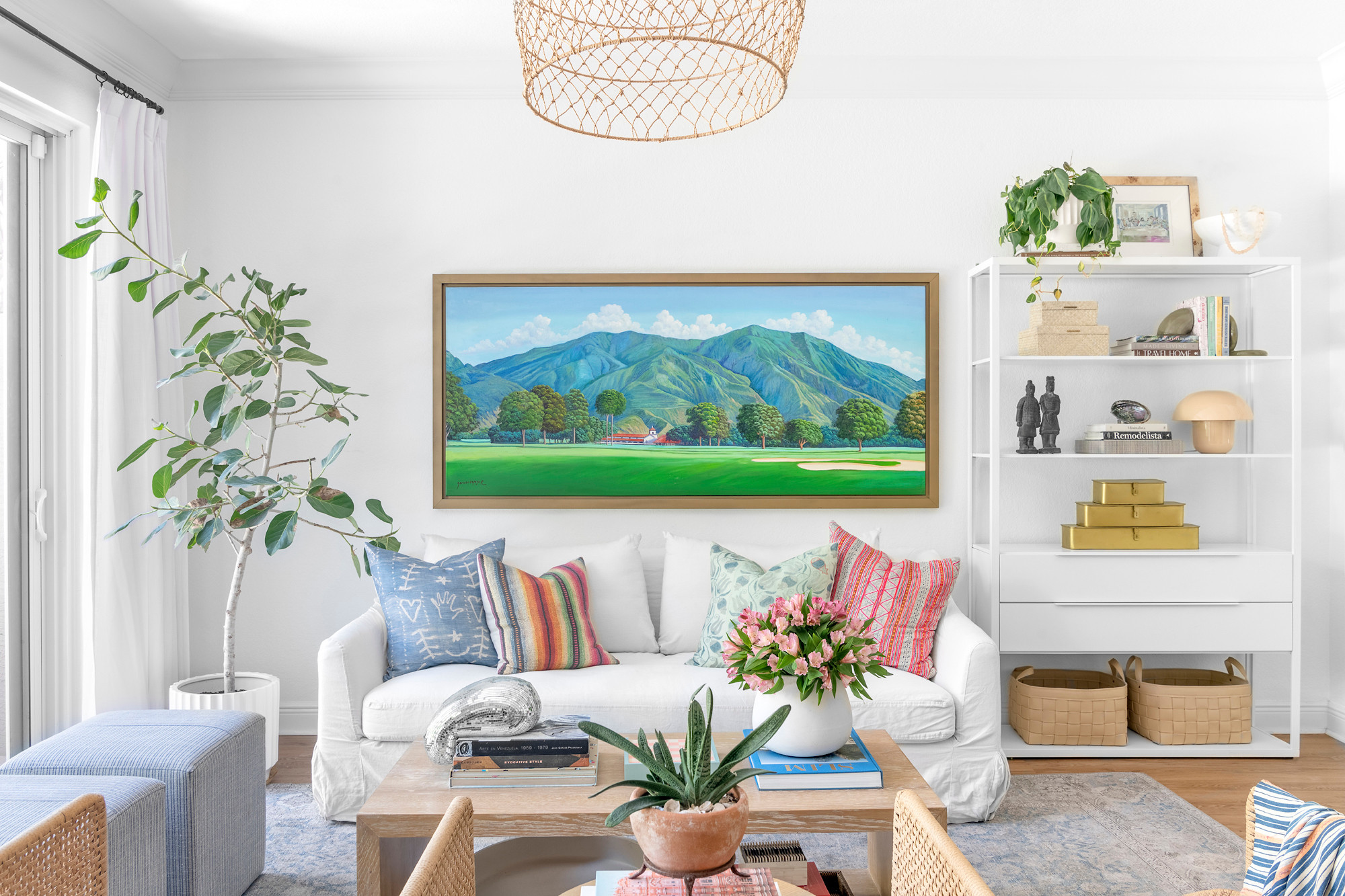 This West Palm Beach living space combines colorful, relaxed decor with personal touches for a welcoming, cozy vibe. A white sofa with textured throw pillows and a custom oil landscape painting from Caracas add warmth and meaning, while natural elements like woven baskets and plants enhance the laid-back aesthetic. Perfect for a vibrant yet serene gathering spot. 

 #LTKHome #LTKFamily