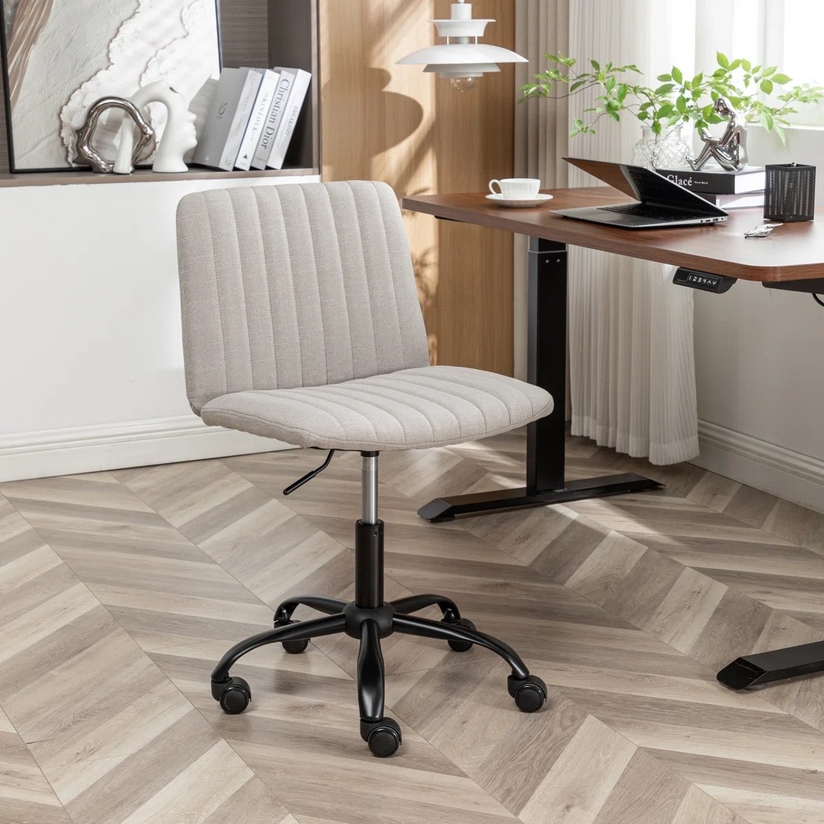 This cream swivel office chair from Wayfair has such an easy, cozy look for a home office. The soft upholstered seat, vertical channel stitching, armless shape, and black rolling base keep it simple without feeling boring. I really like it paired with the warm wood standing desk, white shelving, and leafy greenery, and it also comes in more colors if cream isn’t your thing.