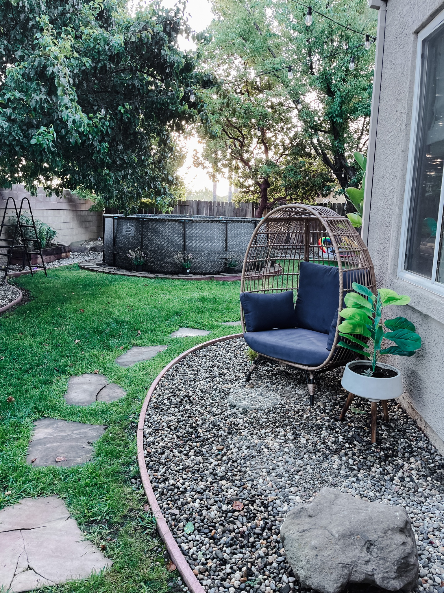 Outdoor living with a large, cozy, egg chair, and an above ground pool. #Outdoor #OutdoorLiving