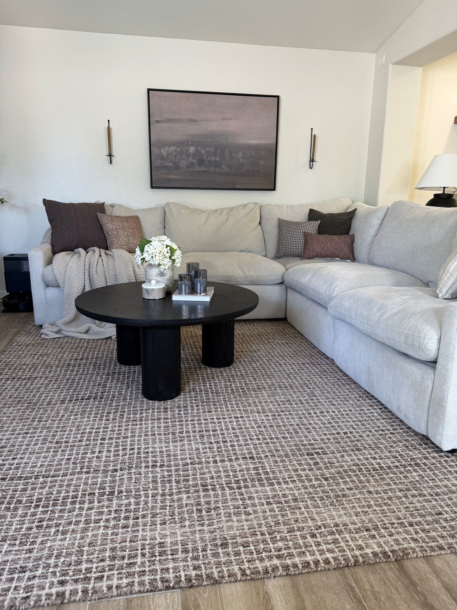 Living room views 😍 2 years later and we are still in love with our sectional! It’s so incredibly comfortable and I love that we have recliners too. 
•
•
•
Neutral living room, light sectional, light grey sectional, light grey couch, round coffee table, black coffee table, abstract wall art, framed canvas art, moody art, cove prints, candle sconces, candle wall sconce, brown rug, brown checked rug, pillow combos for couch, throw pillows for sectional 

#LTKHome