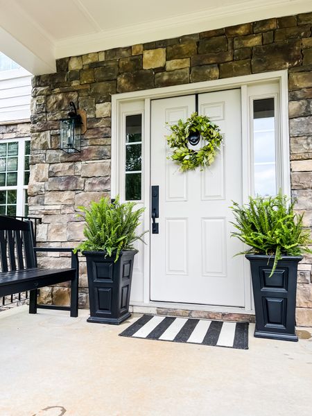 Simple summer porch ideas! Classic tall planters for ferns. Pretty greenery wreath and a striped door mat. Don’t forget the bench for front porch sitting! #frontporch #summerporch #curbappeal 

#LTKSeasonal #LTKstyletip #LTKhome