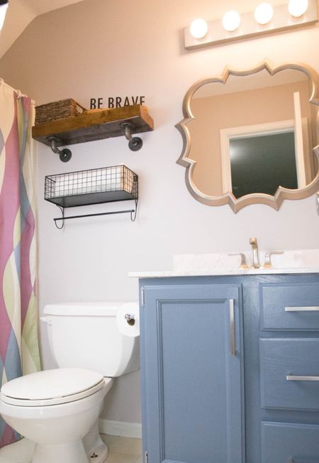 Painted bathroom vanity with large cabinet handles, fun shaped mirror and shelving over the toilet. #bathroom #kidsbathroom 

#LTKhome