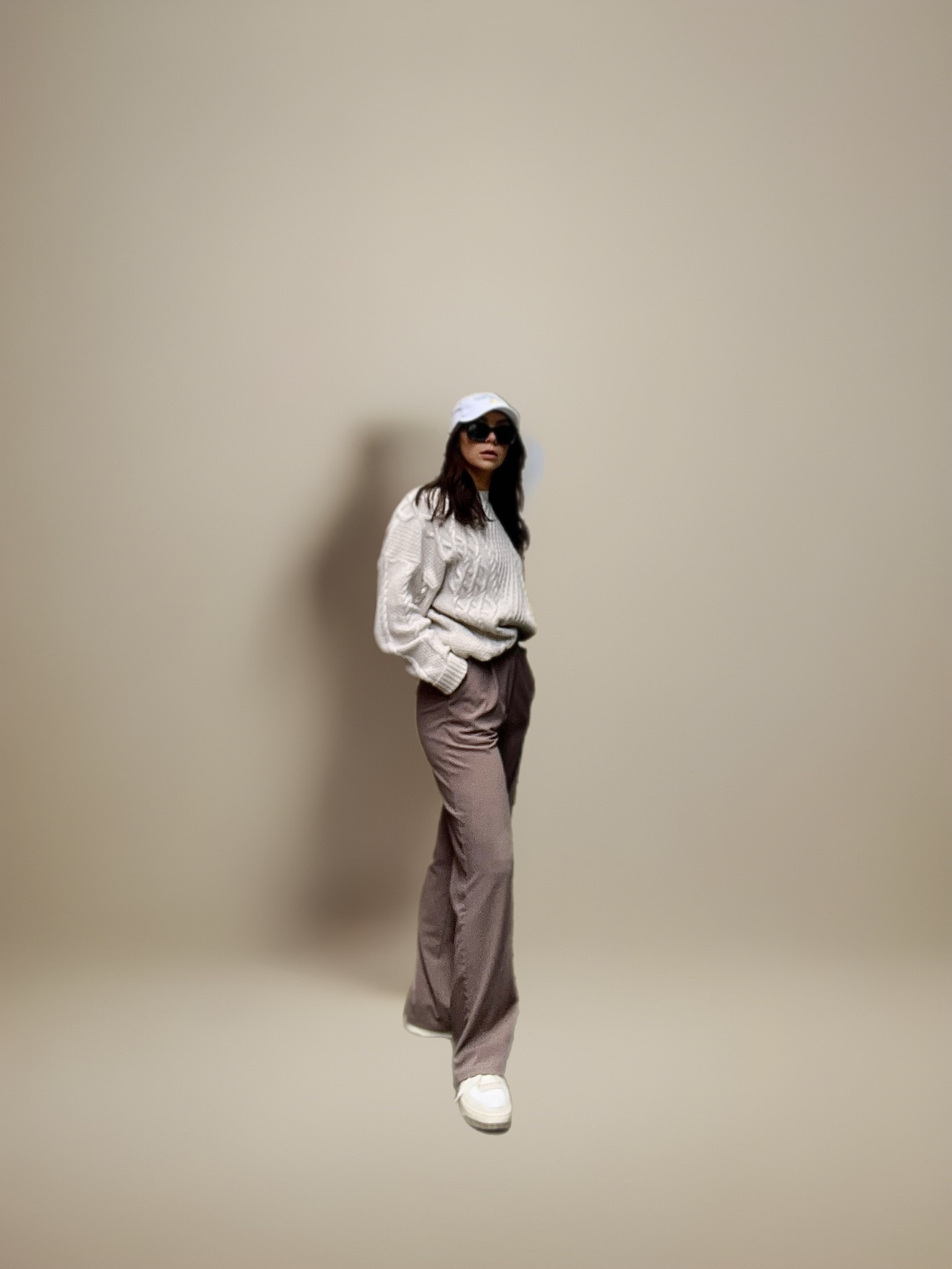 New balance sneaker outfit, white baseball hat, cable knit sweater and brown trouser. Versace sunglasses outfit. Outfit for fall, casual outfit, AI Background 