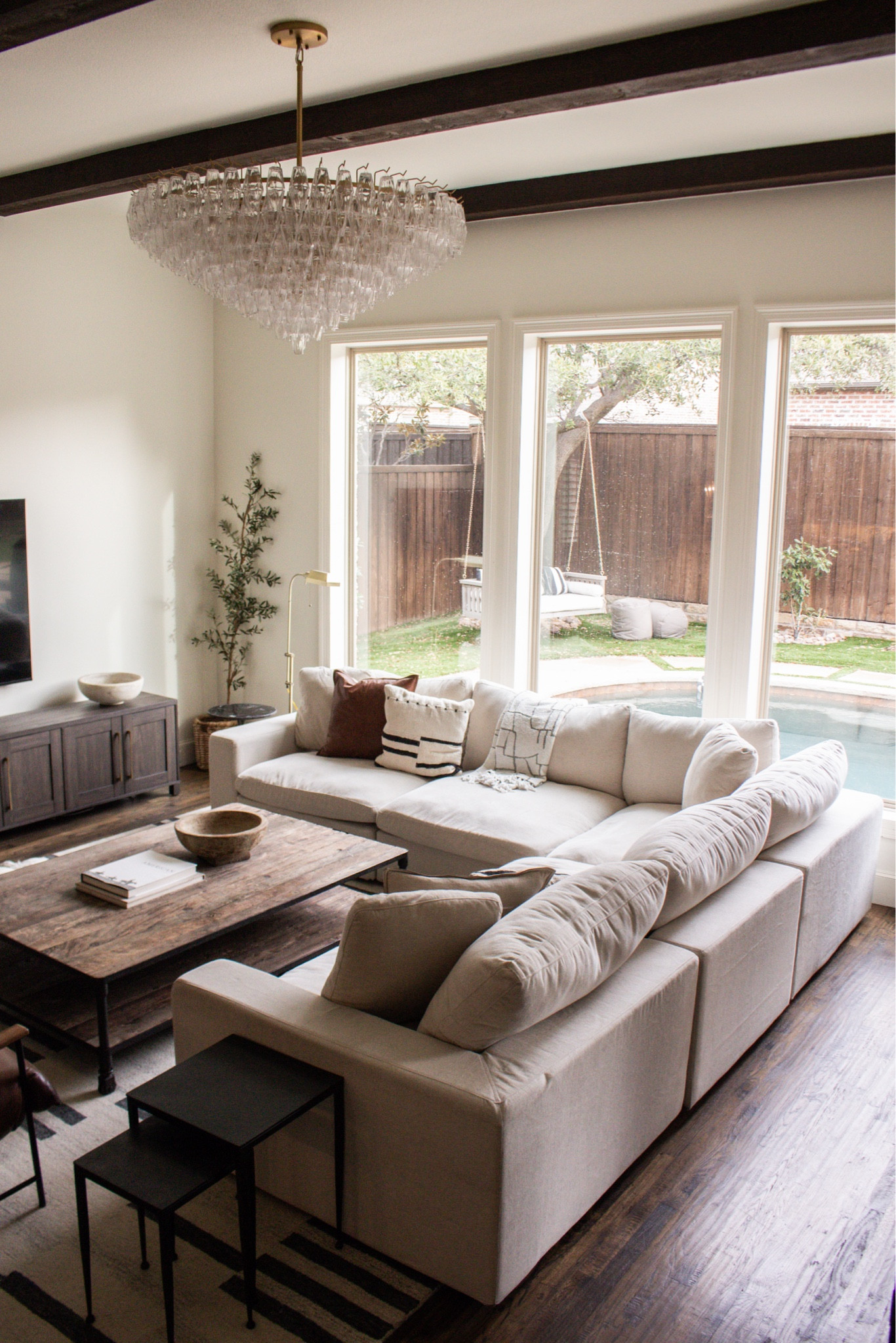 Neutral living room with wood beams and a statement chandelier 🤎 modern farmhouse decor, large sectional sofa, cozy family room, warm wood floors, black accent tables.

#LTKSeasonal #LTKHome