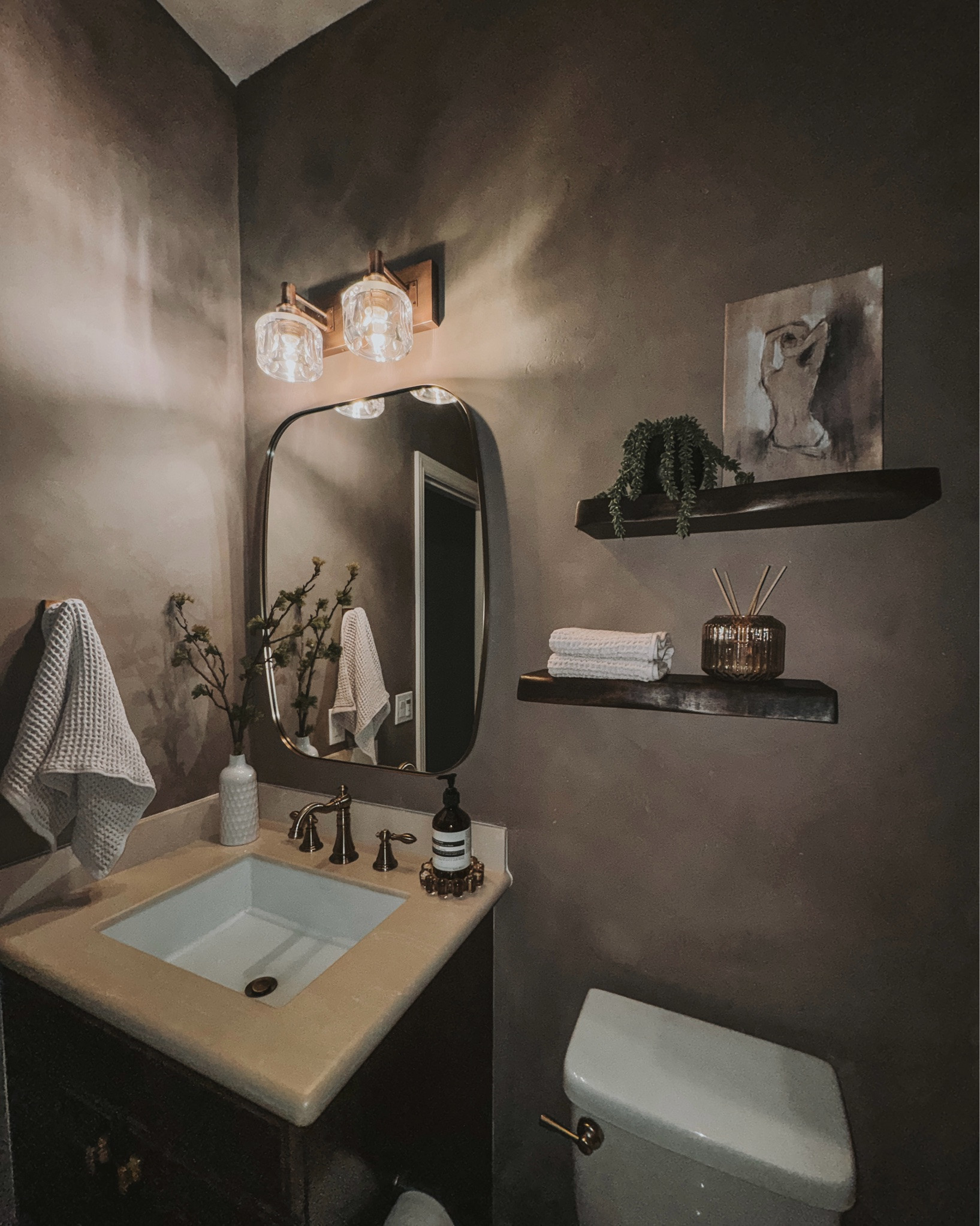 From builder grade to moody modern ✨ Swapped the basic mirror for a vintage-inspired brass oval mirror, added a warm brass faucet, natural wood shelving, and cozy waffle towels to bring in that elevated organic feel. The mix of rich tones, warm metals, and layered textures completely transformed this bathroom into a space that feels custom, timeless, and spa-like.
Sometimes it’s the small details that make the biggest impact 🤎 #modernbathroom #moodynmodern #bathroommakeover #modernorganic #vintagebrass #homedecor #bathroomdesign #interiorstyle