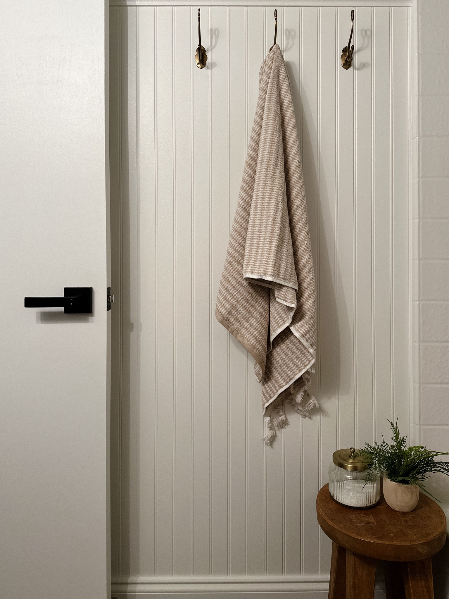 Brass vintage towel hooks, bathroom wooden stool, glass bath salt jar, faux fern, Turkish towel, white beadboard, black door hardware, bathroom decor, bathroom renovation 

#LTKhome #LTKstyletip