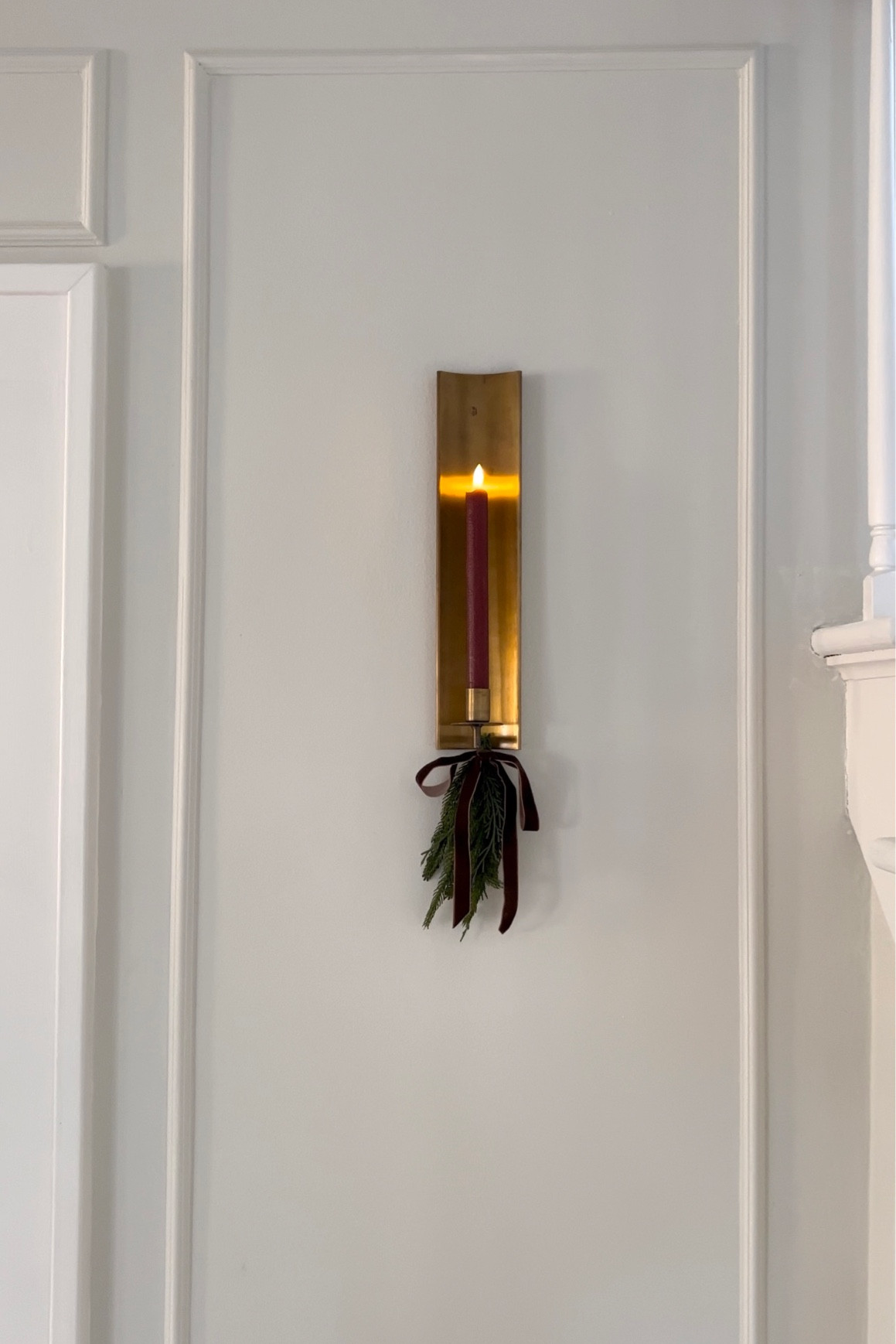 Candle sconce decorated for the holidays with a red candle, greenery, and a festive bow. #holidaydecor #candlesconce 

#LTKHoliday #LTKhome #LTKSeasonal