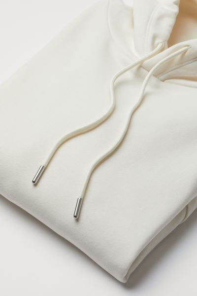 Wide top in sweatshirt fabric with a lined drawstring hood, kangaroo pocket and ribbing at the cu... | H&M (UK, MY, IN, SG, PH, TW, HK)