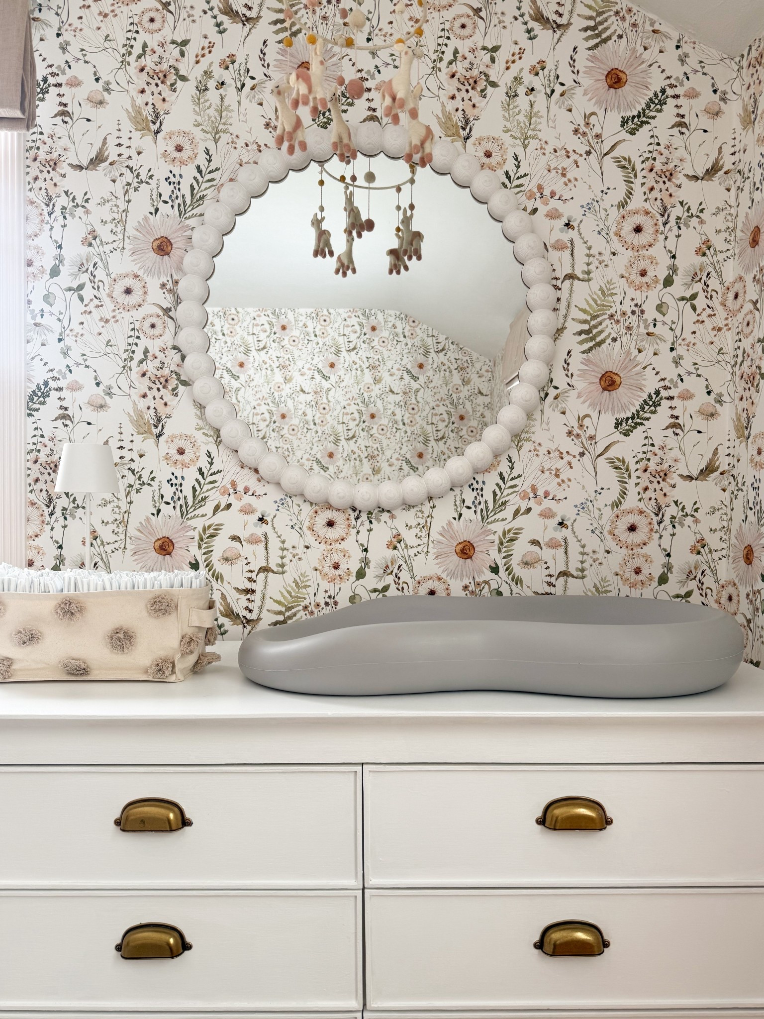 I love how each piece here really has its own moment while still working together so effortlessly. The floral wallpaper adds that soft, detailed backdrop I’m always drawn to, the scalloped mirror brings in just the right amount of shape, and the mobile adds a light, playful touch with movement. Even the dresser with the brass hardware feels like such a classic anchor piece that ties everything together in a really natural way.

nursery changing station decor, floral wallpaper nursery, nursery dresser styling, scalloped mirror decor, nursery mobile ideas, neutral nursery design, brass hardware furniture, cozy nursery details, vintage inspired nursery, soft feminine nursery decor, functional nursery styling girlonthehudson

#LTKHome #LTKKids #LTKBaby
