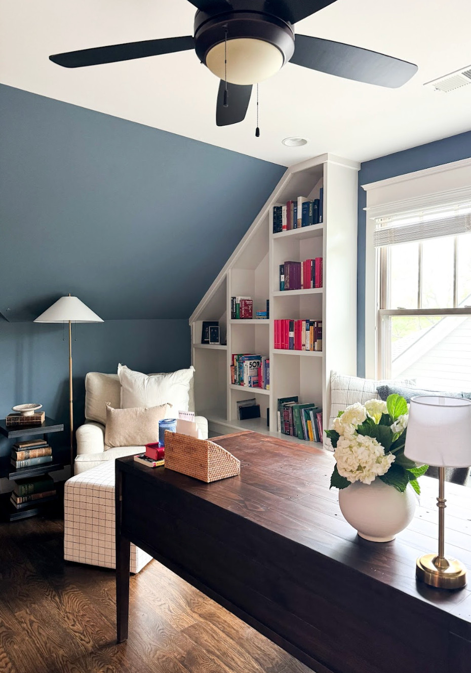 This home office and reading nook is proof that small spaces can make a big impact.✨ To complement the rest of the home, we chose deep blue walls, a warm wood desk, and a soft cream reading chair to create a cozy yet sophisticated retreat. Natural light pours through the window, making it the perfect spot for reading, working, or simply unwinding. The result is a functional, beautiful space my client now uses every single day.💙📚 

 #homeofficedesign #readingnook #cozyinteriors #LTKU #LTKHome