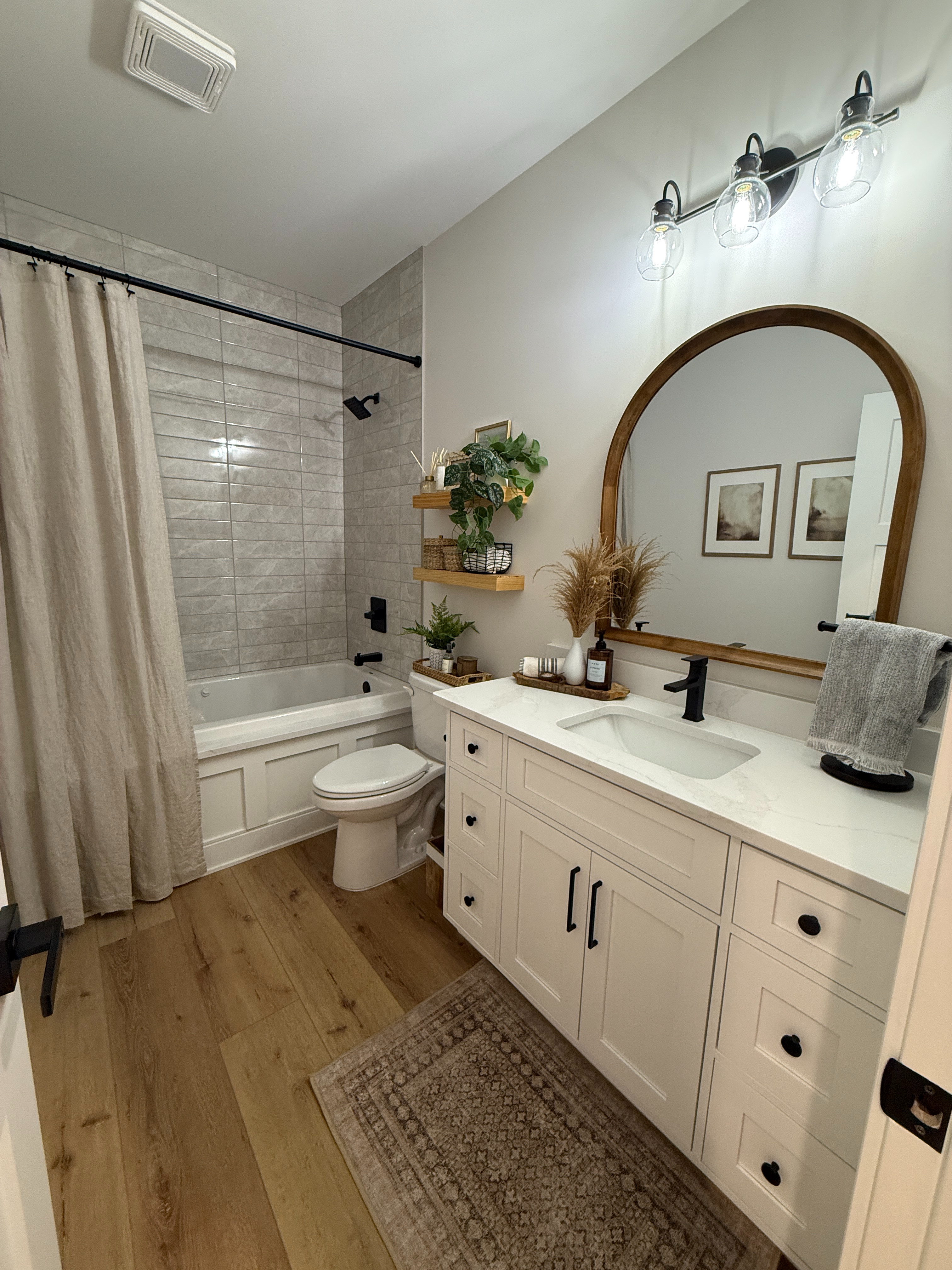Bathrooms may be small, but they never have to be an afterthought.

When it comes to design, bathrooms are often overlooked because of their size, but here’s the thing: they pack a punch.

This was a new construction home, which meant a clean slate (plus some beautifully chosen fixtures to build on). We added an arched mirror with wood trim and floating shelves to bring warmth into the space, paired with a classic linen shower curtain and a washable rug in one of our most-loved, most-used styles. Finished with simple artwork and practical decor, this guest bath quickly became one of our favorite spaces in the house and we think their guests are going to love it just as much. 

 #LTKHome