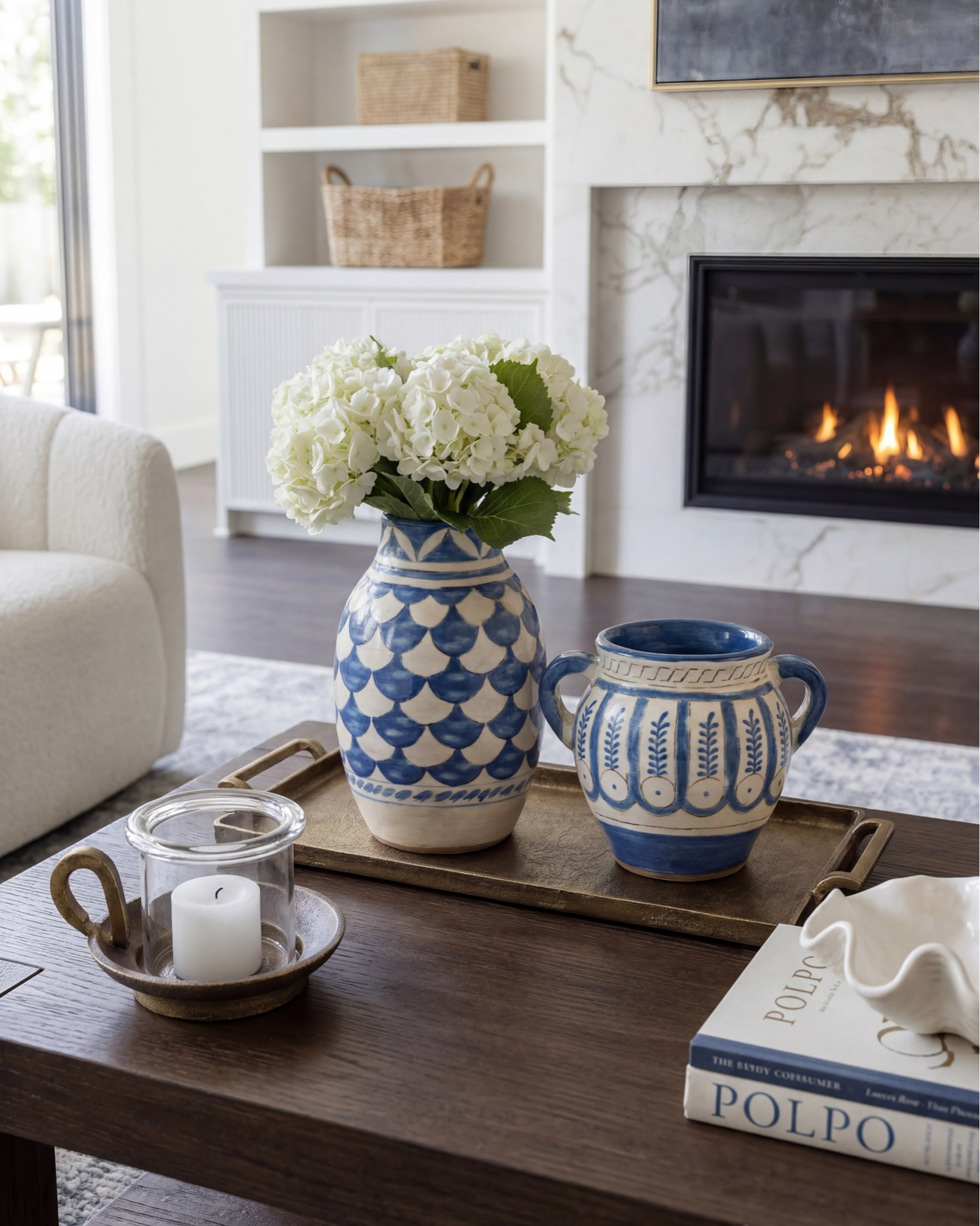 Layered transitional living room inspiration with luxe marble fireplaces, moody floral wallpaper, dark wood beams, boucle accent chairs, and designer lighting details. Shop the look for a cozy modern organic home with high-end furniture, neutral decor, blue accents, brass lighting, textured rugs, and timeless statement pieces. Perfect inspiration for anyone searching for transitional style living rooms, modern farmhouse decor, marble fireplace ideas, designer coffee tables, and curated home accessories. 

Shop this space: • Marble fireplace surround • Dark wood ceiling beams • Brass chandelier lighting • Boucle accent chairs • White slipcovered sofa • Blue patterned throw pillows • Dark wood coffee table • Abstract framed artwork • Textured neutral area rug • Ceramic table lamps • Built-in shelving decor • Decorative woven baskets • Floral wallpaper mural • Fringe ottomans • Fluted console table • Brass wall sconces • Ribbed cabinetry details • Marble slab backsplash • Glass cabinet fronts • Wine fridge built-in • Blue and cream vintage style rug • Modern ceramic vases • Coffee table styling books • Neutral cozy throw blankets

#LTKsale #LTKhome #LTKstyletip