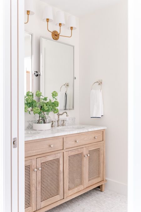 Our renovated guest bathroom in our last house includes a beautiful polished nickel faucet, a double sink cane vanity with marble top, a silver pivot wall mirror, a paint dipped vase with faux greenery, silver bathroom hardware, white hand towels with a navy blue border and brass sconce lights. Other items not shown include classic white subway tile, a white shower curtain and a gold star light flush mount. 

bathroom inspo, bathroom cabinet, bathroom decorating, bathroom countertop, bathroom hand towels, bathroom mirror, amazon home décor, amazon bathroom accessories, pottery barn vanity, lowes tile, serena and lily bathroom, serenaandlily vase, pb home, pottery barn mirrors, bathroom vanities, bathroom hardware, bathroom mirrors, bathroom accessories set, coastal decorating, coastal design, coastal inspiration    


#LTKfindsunder50 #LTKfindsunder100 #LTKSeasonal #LTKhome #LTKsalealert #LTKstyletip #LTKstyletip #LTKfindsunder100

#LTKhome #LTKSeasonal #LTKsalealert