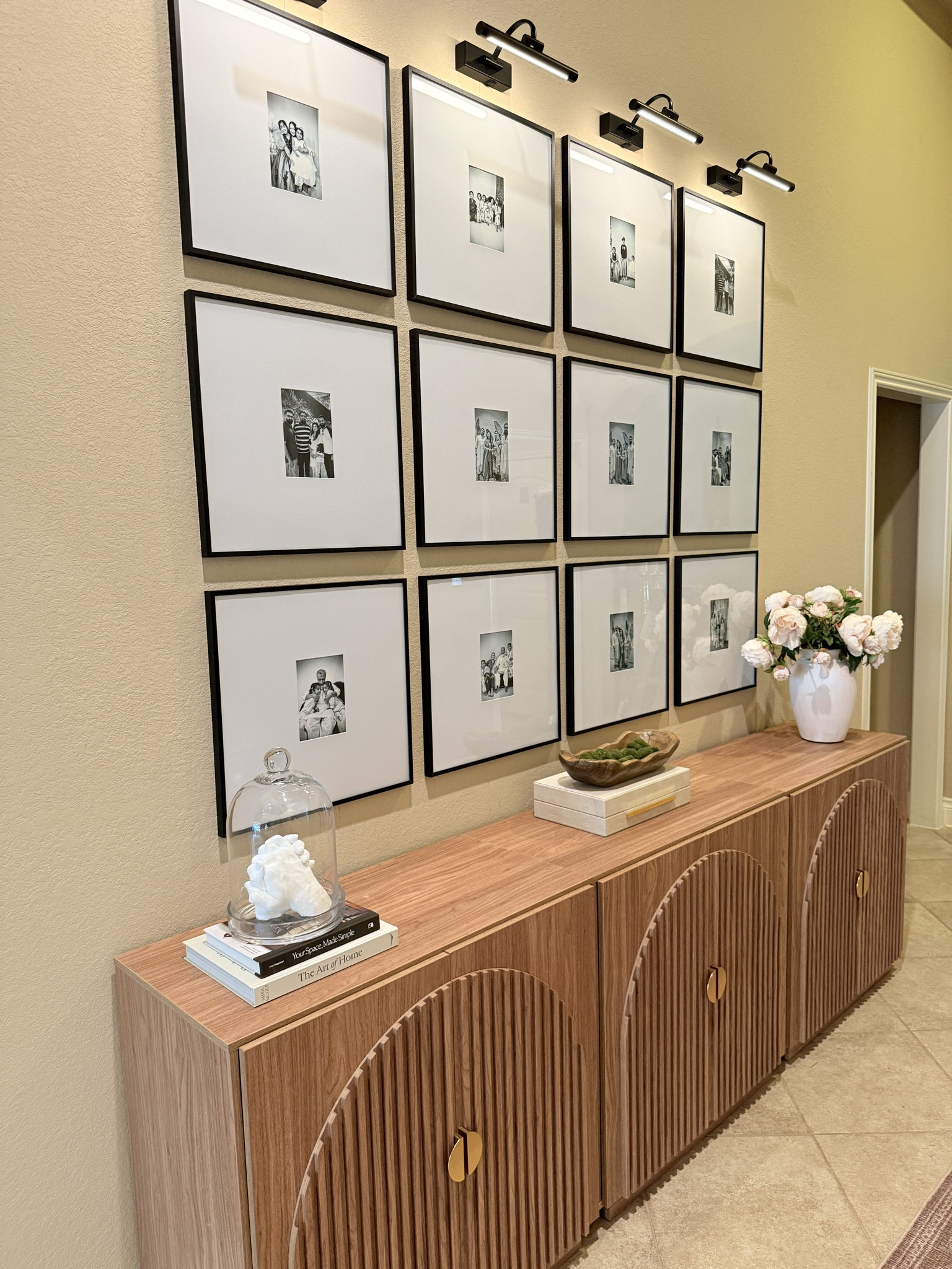 Making memories the centerpiece.
This gallery wall of 12 family photos is one of my favorite spots in the house. I paired it with fluted cabinets to create a bigger credenza look, styled with peony flowers, coffee table books, and lit with battery-operated picture lights for a cozy glow. @amazon @wayfair @walmart 

#LTKHome #LTKSaleAlert #LTKStyleTip