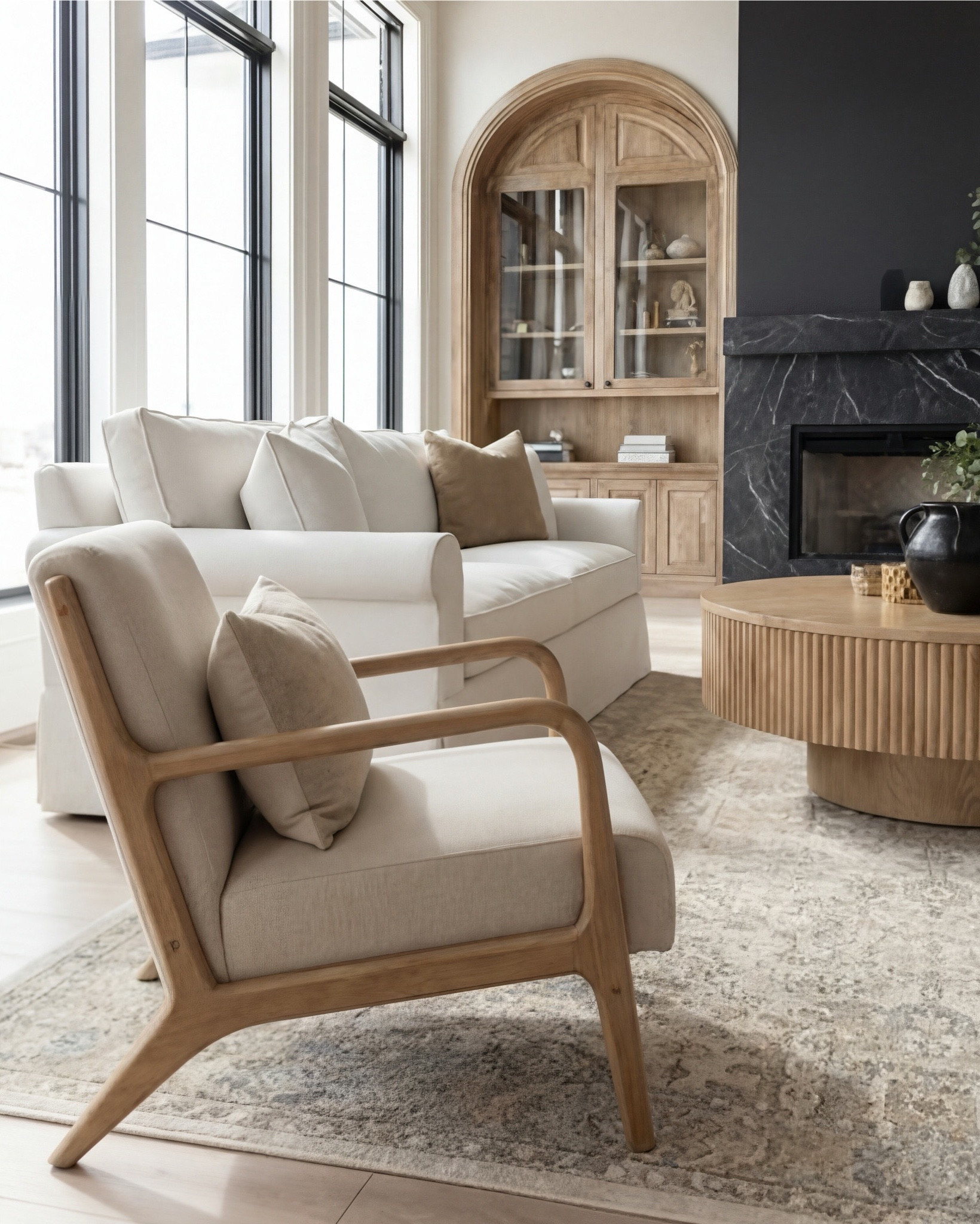 A living room that whispers calm instead of shouting for attention. 🤍

The contrast of the matte black fireplace against the soft oak built-ins is everything—bold, sculptural, and still unbelievably serene. The arched cabinetry brings in that old-world craftsmanship energy, but the light wood keeps it fresh and modern.

Neutral seating, warm woods, and layered textures make the space feel grounded and effortless. Nothing competes—every piece harmonizes. This is what quiet luxury looks like when it’s lived in, not staged.

Shop the Look:
• Cream upholstered sofas
• Light wood accent chairs
• Round fluted coffee table
• Black stone fireplace surround
• Warm oak arched built-ins
• Neutral patterned area rug
• Textured knit throw
• Ceramic vases + greenery

#LTKsale #LTKhome #LTKstyletip
