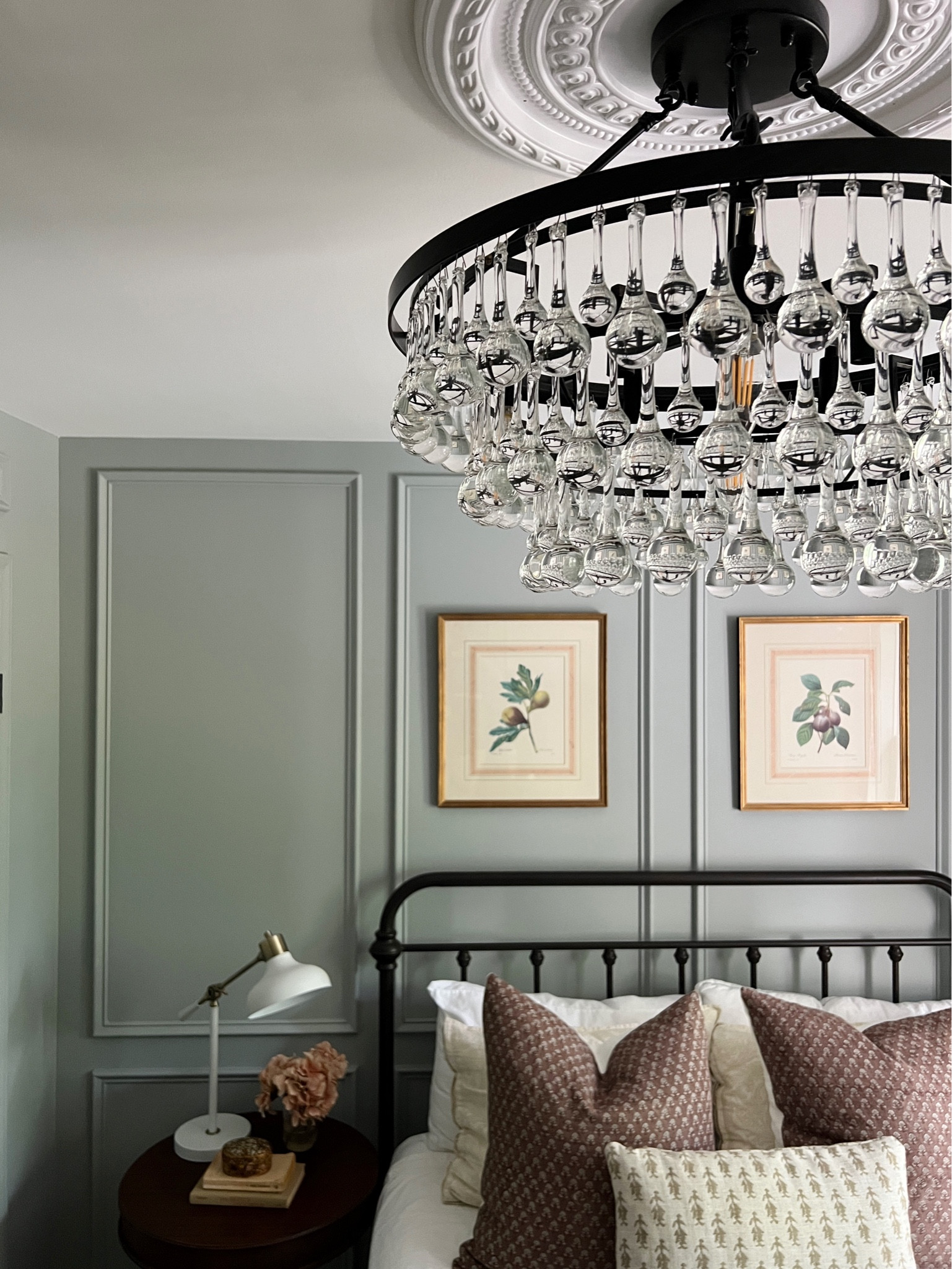 Chandelier in bedroom // blue green bedroom with plum pillows // wrought iron bed // classic bedroom // floral art over bed // black chandelier // classic bedroom lighting 

#LTKhome