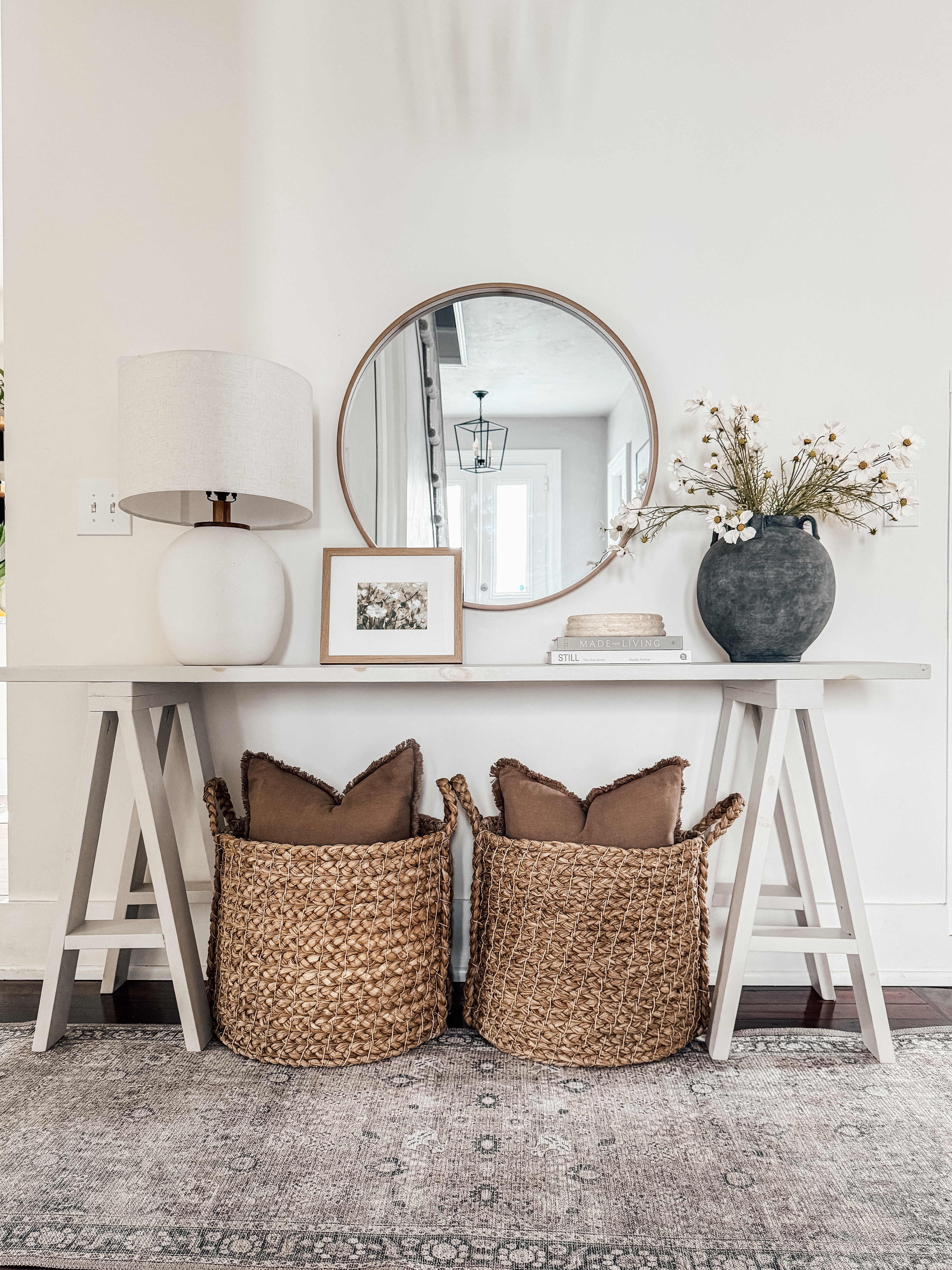 Freshen up your entryway for summer ☀️ This light and airy console table setup is full of texture and timeless details—perfect for creating a warm welcome. I styled it with woven baskets (great for storing shoes or pillows!), soft linen throw pillows, a ceramic vase with faux cosmos stems for that breezy, summer floral feel, and a white table lamp to keep things light and clean. The large round mirror opens up the space, and coffee table books + seasonal floral art in a wood frame add the finishing touch.

Tap to shop this easy, elevated summer look 🤍

#LTKhome #entrywaydecor #consoletabledecor #summerhomestyle #neutraldecor #organicmodern #wovenbaskets #fauxflowers #roundmirror #homeinspo #targetstyle #amazonfinds #decoronabudget #homerefresh #coffeetablebooks #summerentryway

 

 #LTKSummerEdit #LTKSeasonal #LTKHome