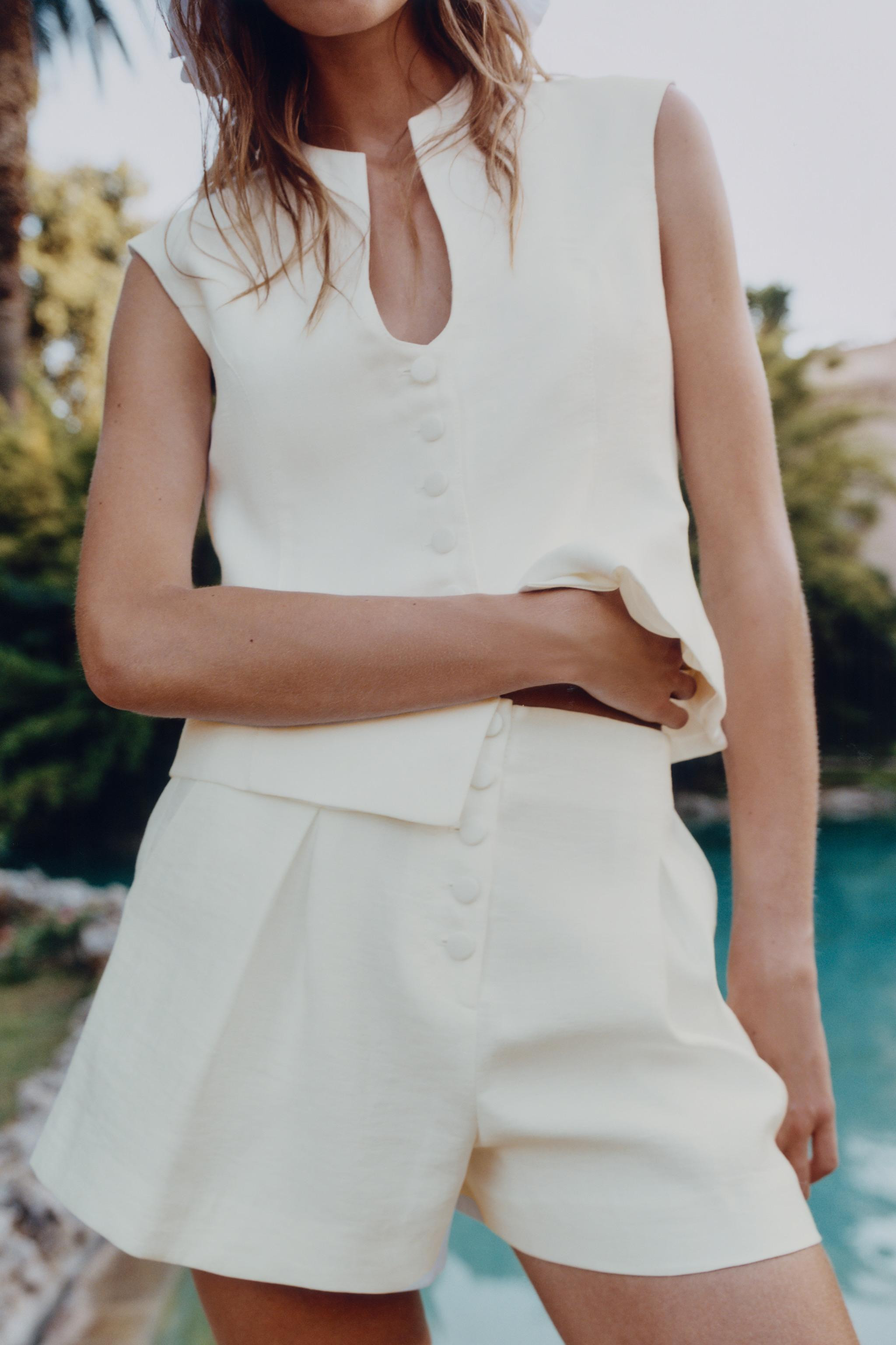 Sleeveless round neck top with a V-neckline. Flared hem. Front closure with matching covered butt... | Zara US