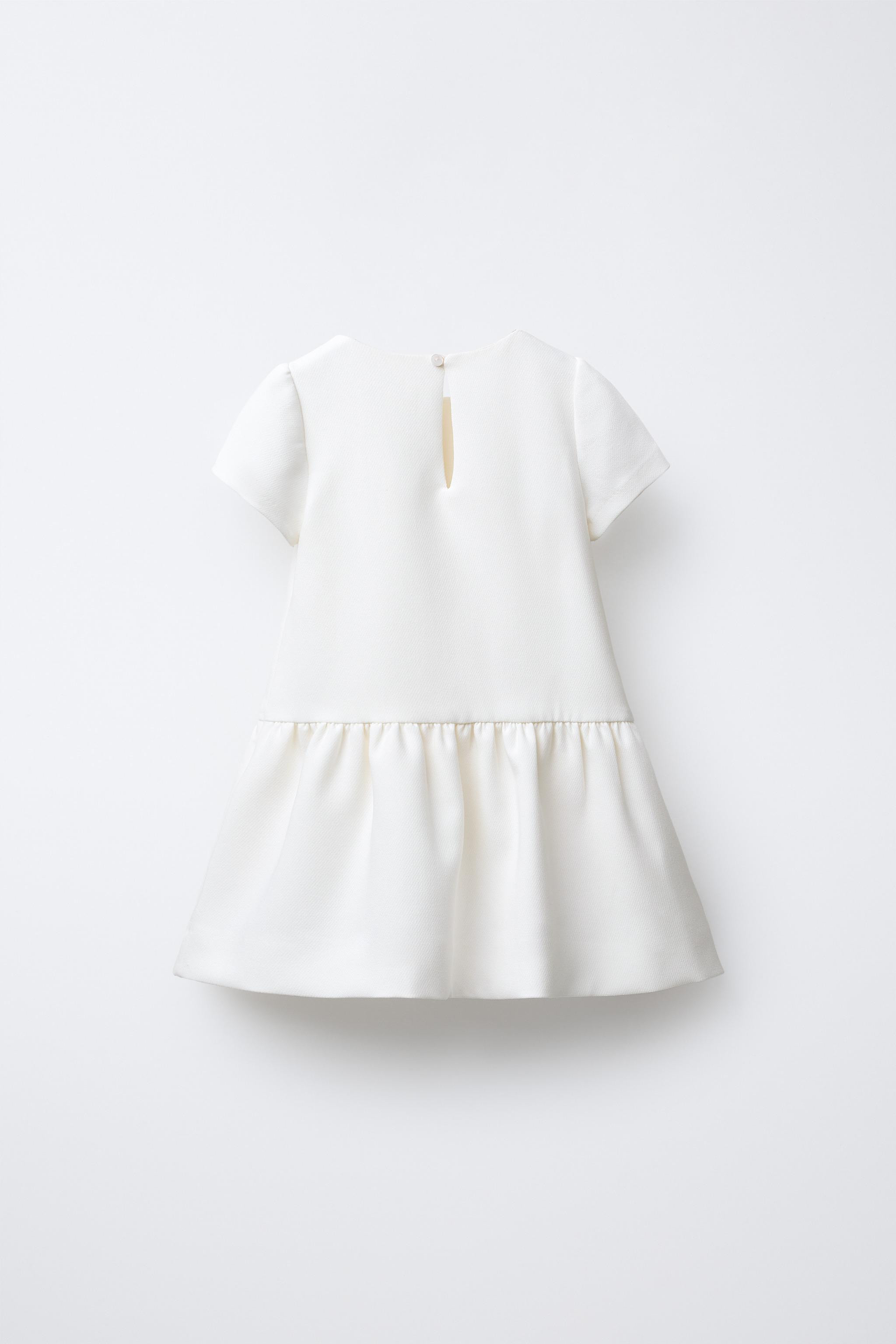 Tulle top with round neck and long sleeves with elastic cuffs. Ruffled appliqué. Teardrop button... | Zara US