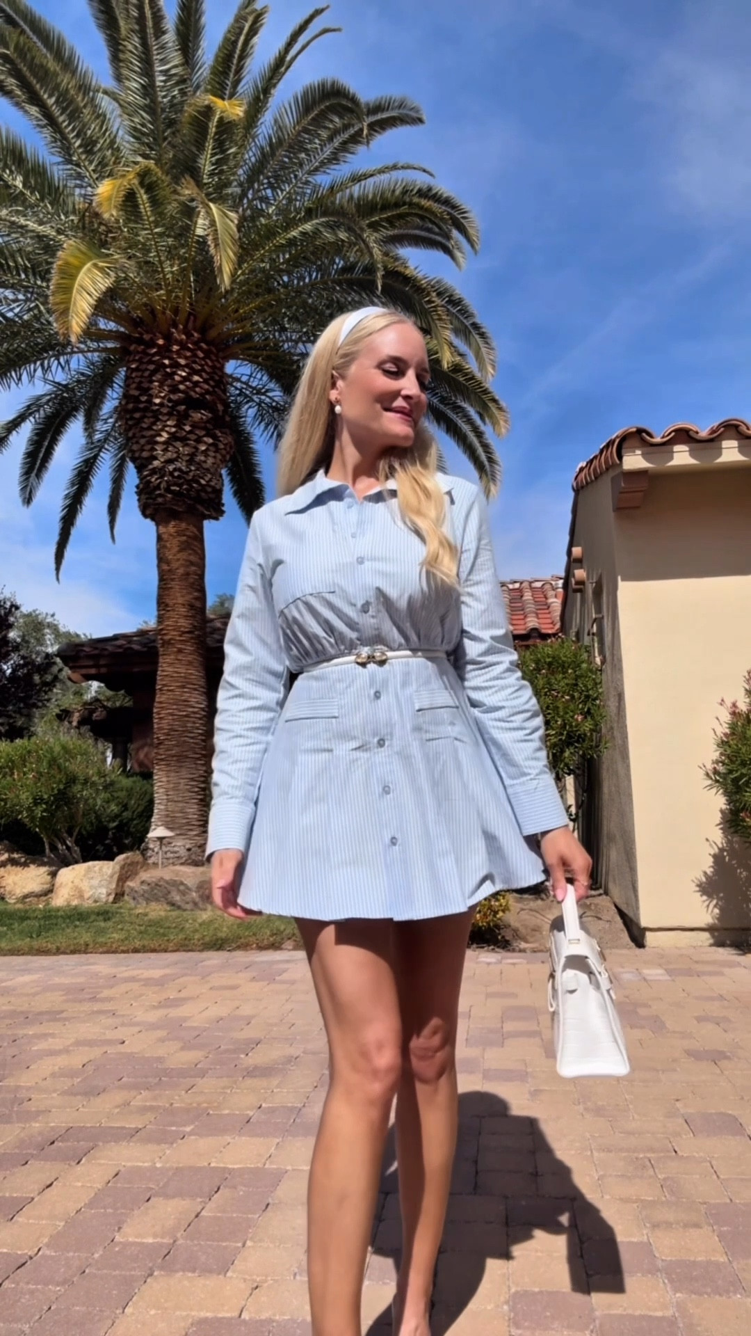 What I'm wearing in Lake Las Vegas for a warm spring day 🦋☀️🌴 I paired this blue pinstriped shirtdress with a skinny belt, lace pumps, pearl earrings and a white top handle bag - plus a cute white headband 🤍🕊️ I wanted my accessories to glam it up a bit & make it a little more feminine to offset the menswear print and collared shirt. Such a fun dress and this style is all over the place right now!! 🩵🤍🩵  

#LTKWatchNow #LTKSeasonal #LTKStyleTip