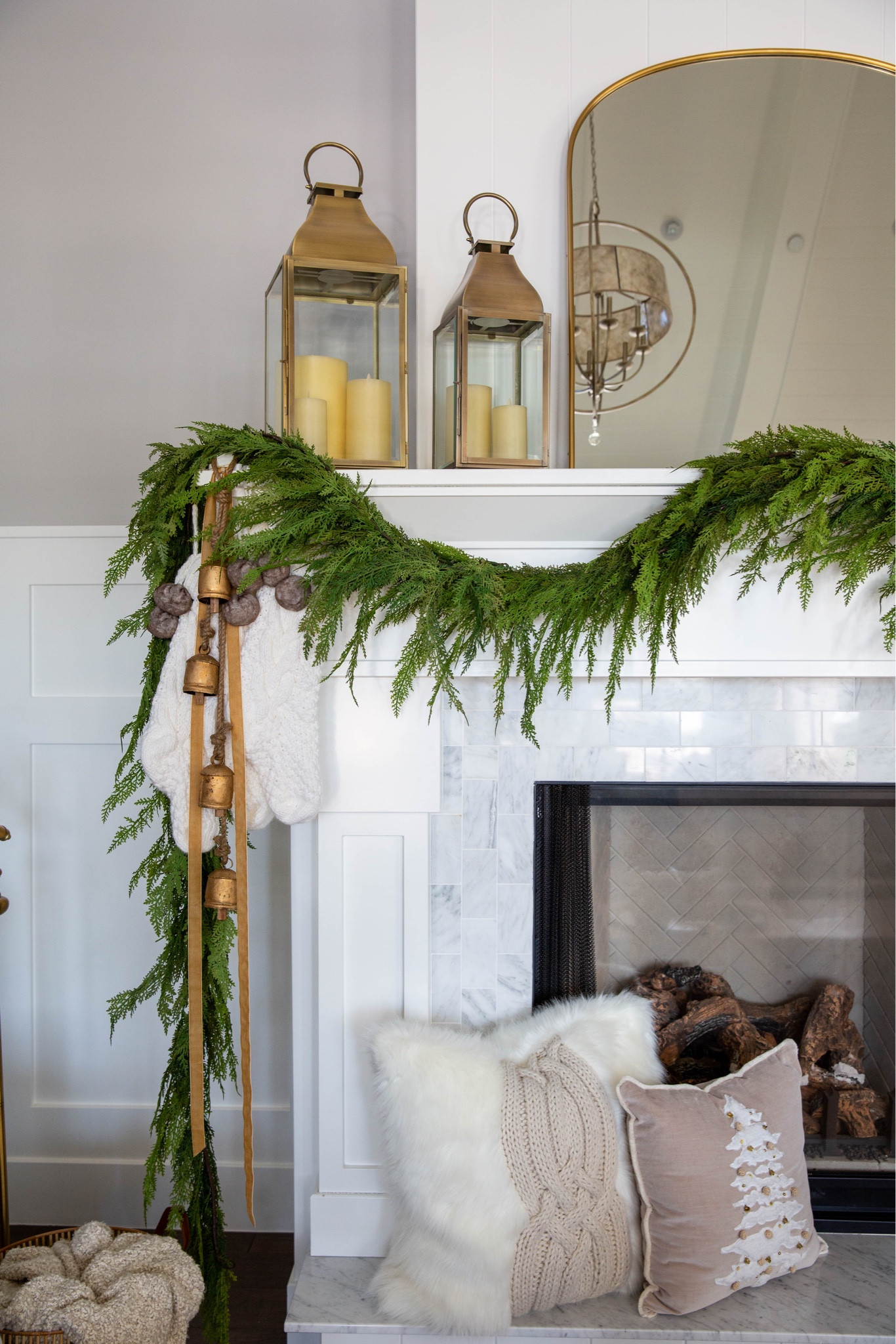 Holiday mantel decor! 
Garland 
Lanterns 
Bells 
Holiday pillow 
Gold mirror 
Fireplace mantle decor 

#LTKSeasonal #LTKHoliday #LTKhome