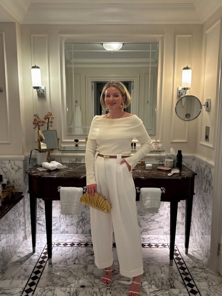 Date night spring outfit idea - white tailored trousers, cream off the shoulder knit top, cult Gaia gold clutch bag, white heeled sandals, oversized flower earrings & tan Kelly belt  

#LTKSeasonal #LTKeurope #LTKstyletip