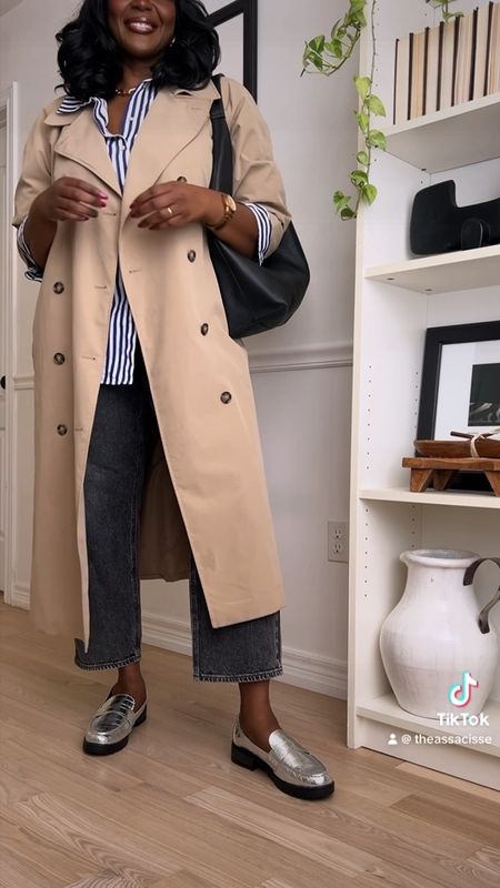 Plus size spring outfit idea featuring a long trench coat, blue striped button up shirt, grey jeans, metallic loafers and green baseball hat. 

#LTKshoecrush #LTKstyletip #LTKplussize