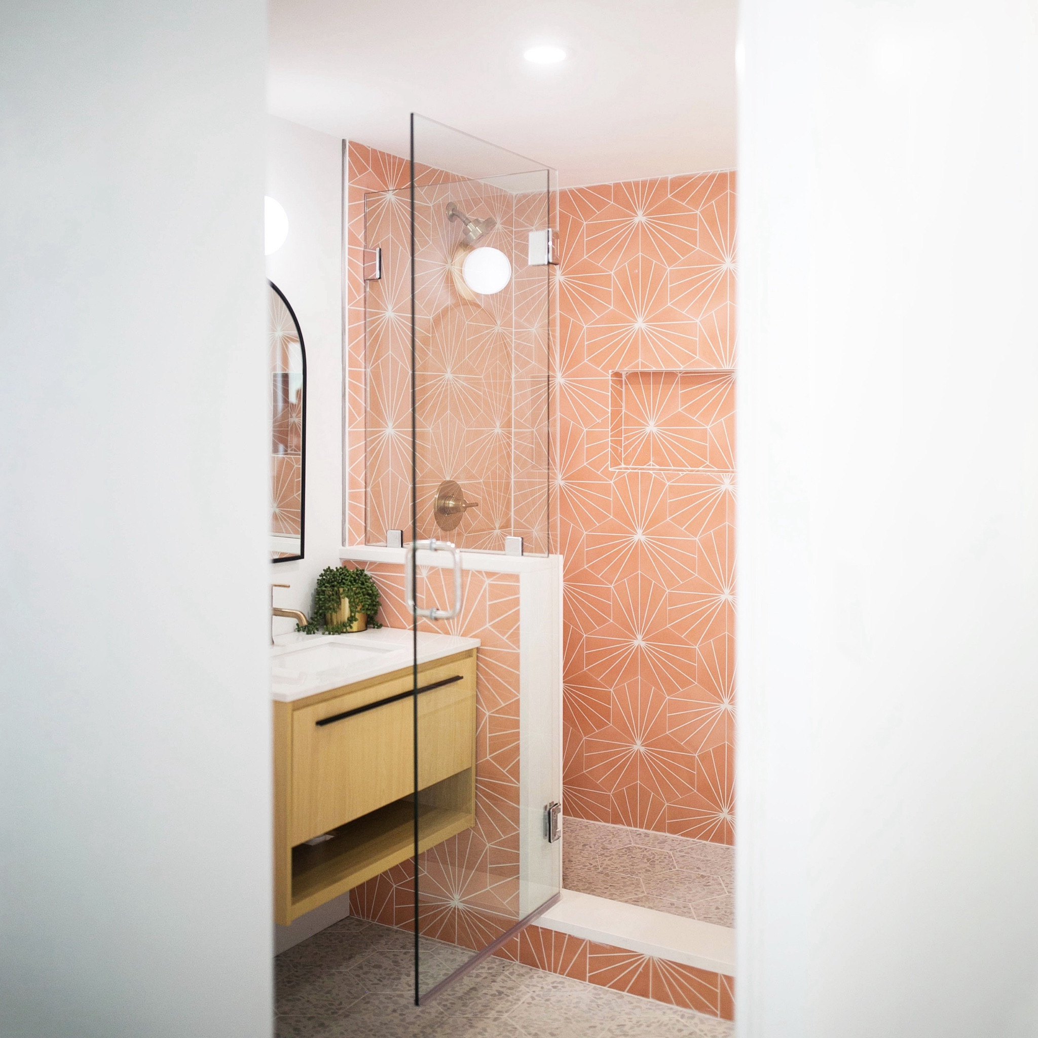 have you ever considered converting a standard tub/shower combo into a walk in shower? we made this decision in the primary bath at the #goldengirlscondo to make the unit more accessible and functional for everyday life. we loved this pink starburst pattern cement tile so much that we added it to the outside walls of the shower as well to make even more of a statement. the faux terrazzo tile used on the floor is the perfect complement and adds a bit of texture and sparkle to the space. #dwelloctober

#LTKhome