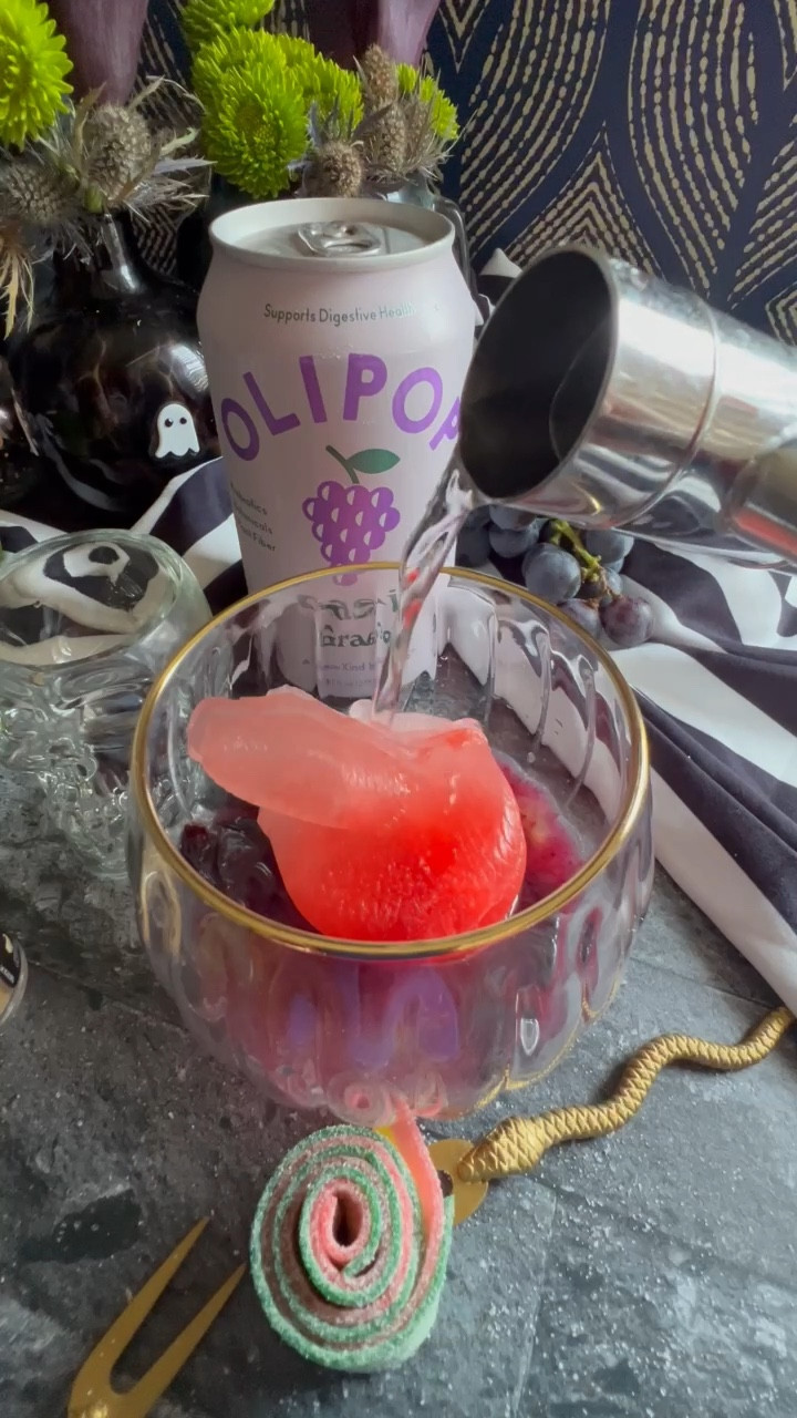 Ready for “grape”ness?! Time for some “gin”spiration as I grab a classsic grape and create a cocktail as an ode to the Ghost with the Most babe.  Here is how to cast this spell: 
Muddle Concord grapes in the bottom of your glass.  Add the juice of 1 lime. Then ice (mine was in serpent form with a little grenadine in it).  Pour 1.5 oz of gin over your ice then top with Olipop Grape.  Garnish with edible glitter, a rosemary spring and a sour belt swirl.  
“Let’s turn on the juice and see what shakes loose” -Beetlejuice
Halloween cocktail party 

#LTKHalloween #LTKVideo #LTKParties