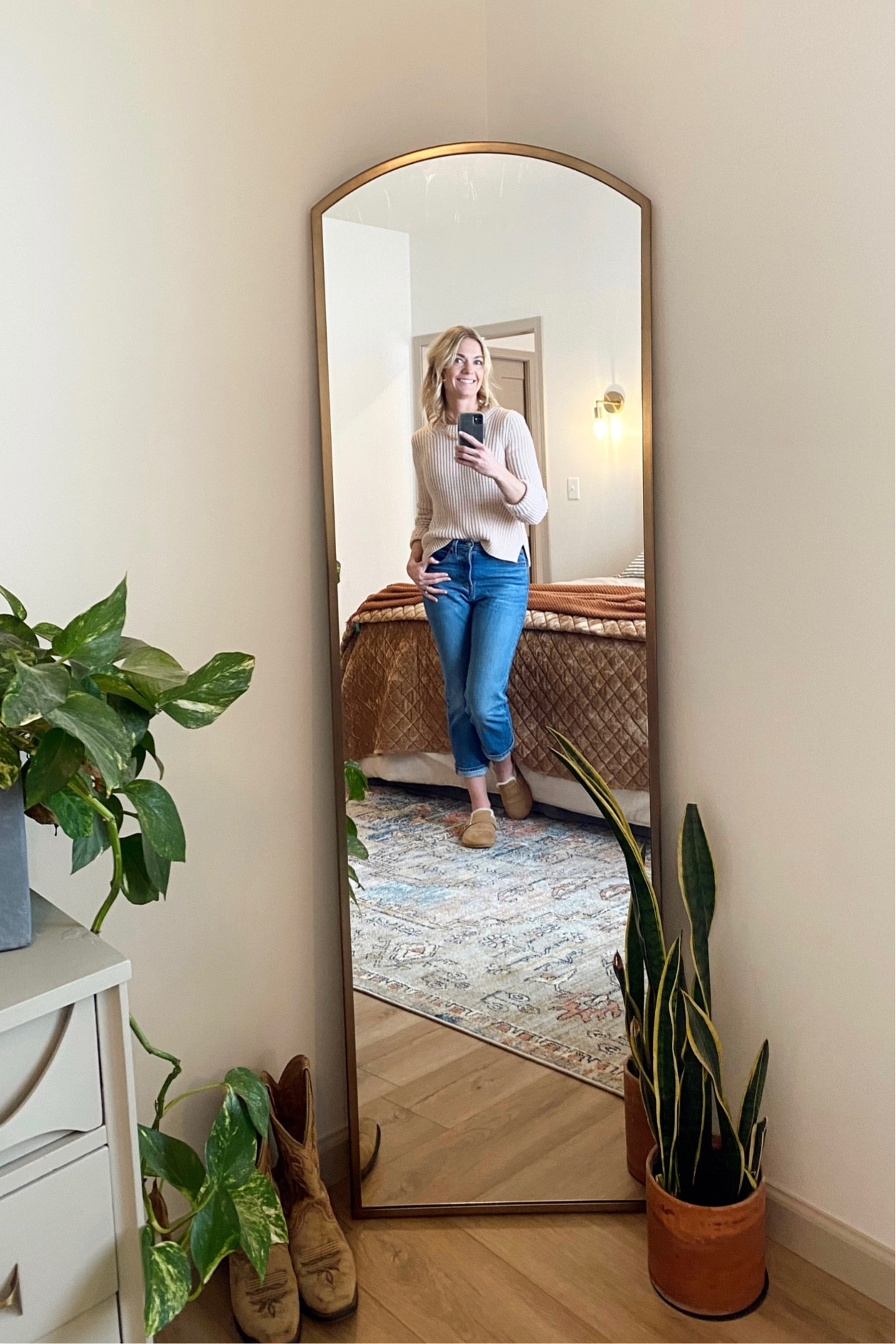 Boho primary bedroom with arched floor mirror, plants, cozy bedding, and a colorful rug to pull it all together  

#LTKhome #LTKFind