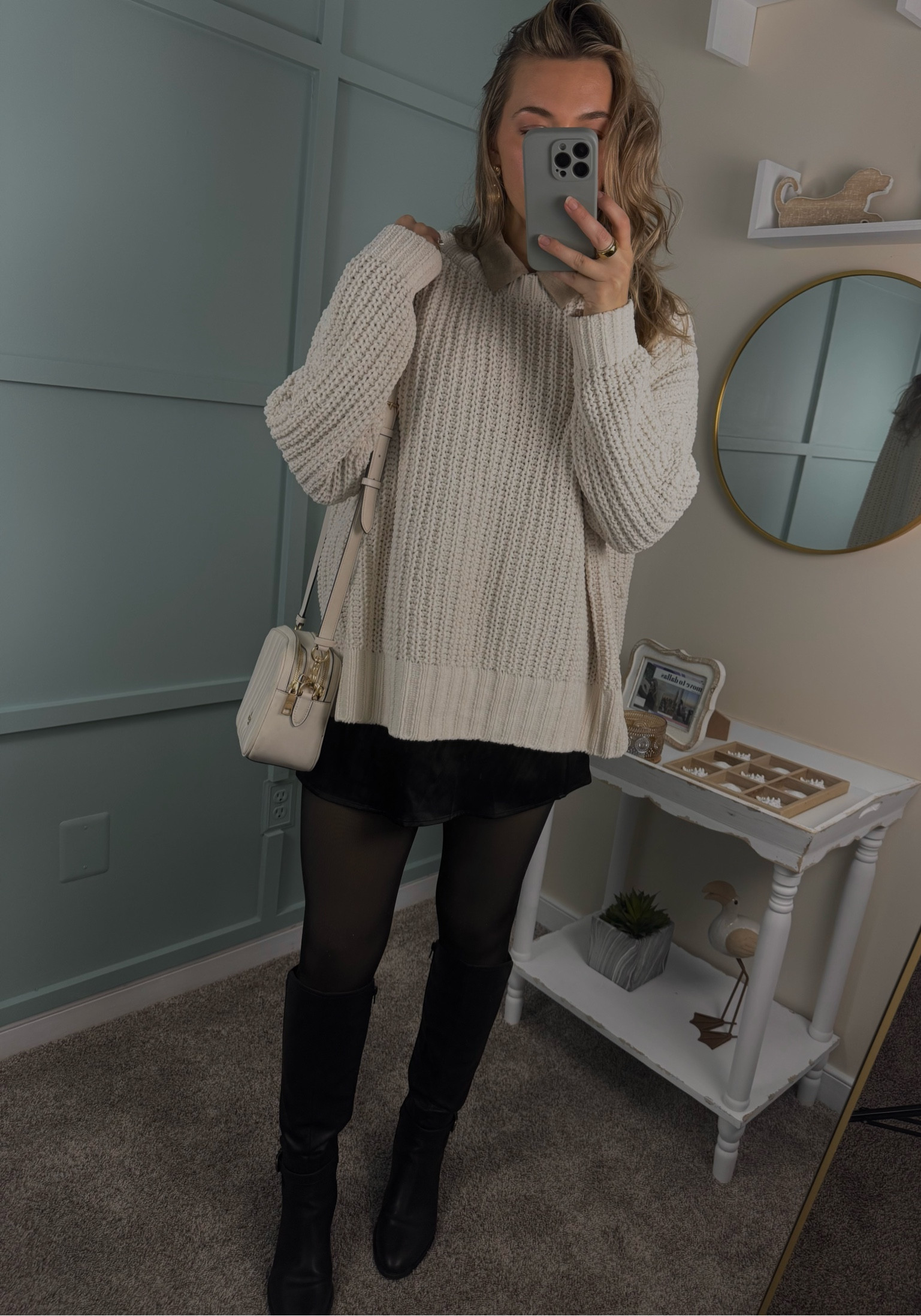 This chic winter look features a cozy white cable knit oversized sweater layered over a beige collared shirt for a stylish, layered vibe. Paired with a sleek black satin mini skort, sheer tights, and tall black leather boots, this outfit exudes both comfort and sophistication. Finished off with a classic white Coach crossbody bag and elegant gold jewelry for the perfect touch of luxury. #WinterStyle #CozyChic #FashionInspo #OOTD #HolidayLook #LayeredStyle #BlackBoots #SatinSkirt #CoachBag #GoldJewelry 

#LTKBeauty #LTKStyleTip #LTKSaleAlert