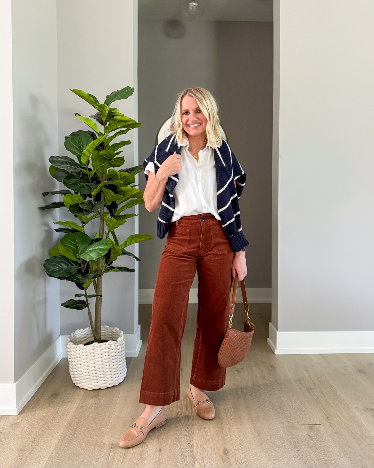 Preppy fall layers: white button-down, striped sweater over my shoulders, rust corduroy pants from @quince, and loafers 🤎
