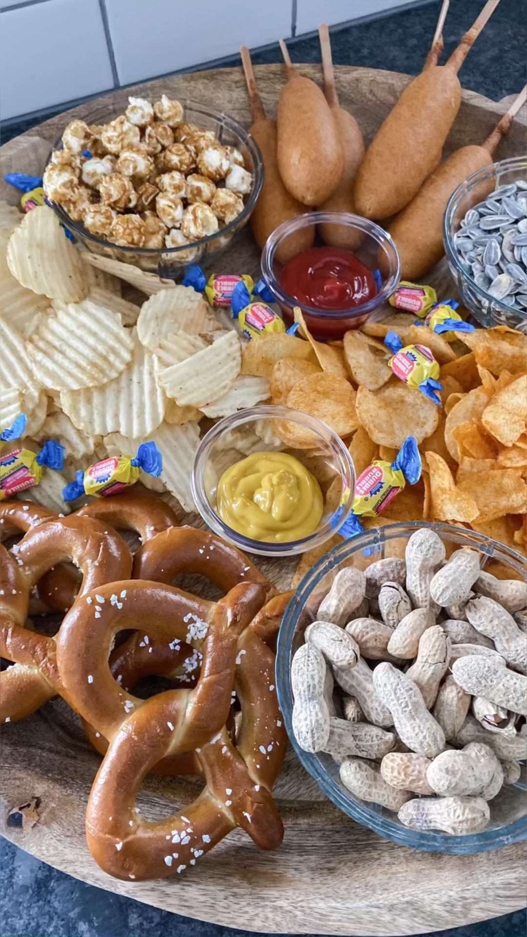 BASEBALL SNACK TRAY! ⚾️

Baseball season is wrapping up and games are getting even more exciting! I love making quick little (or big 😅) snack boards that make ordinary evenings a special event.

My favorite wooden tray by Hearth and Hand at Target has come in handy so many times. It's the perfect size and shape for a fun family snack board for any occasion.

For our baseball snack board, I added two varieties of potato chips, cracker jacks, corn dogs, sunflower seeds, peanuts, soft pretzels, and ketchup and mustard for dipping. I also sprinkled some wrapped bubble gum on top to make it even more festive. Honestly though, how fun?!

Just like you're at the ballfield, but in the comfort of your home. This homebody mama approves! 

What would you make sure is on your baseball snack board?	

#LTKSeasonal #LTKfindsunder50 #LTKVideo