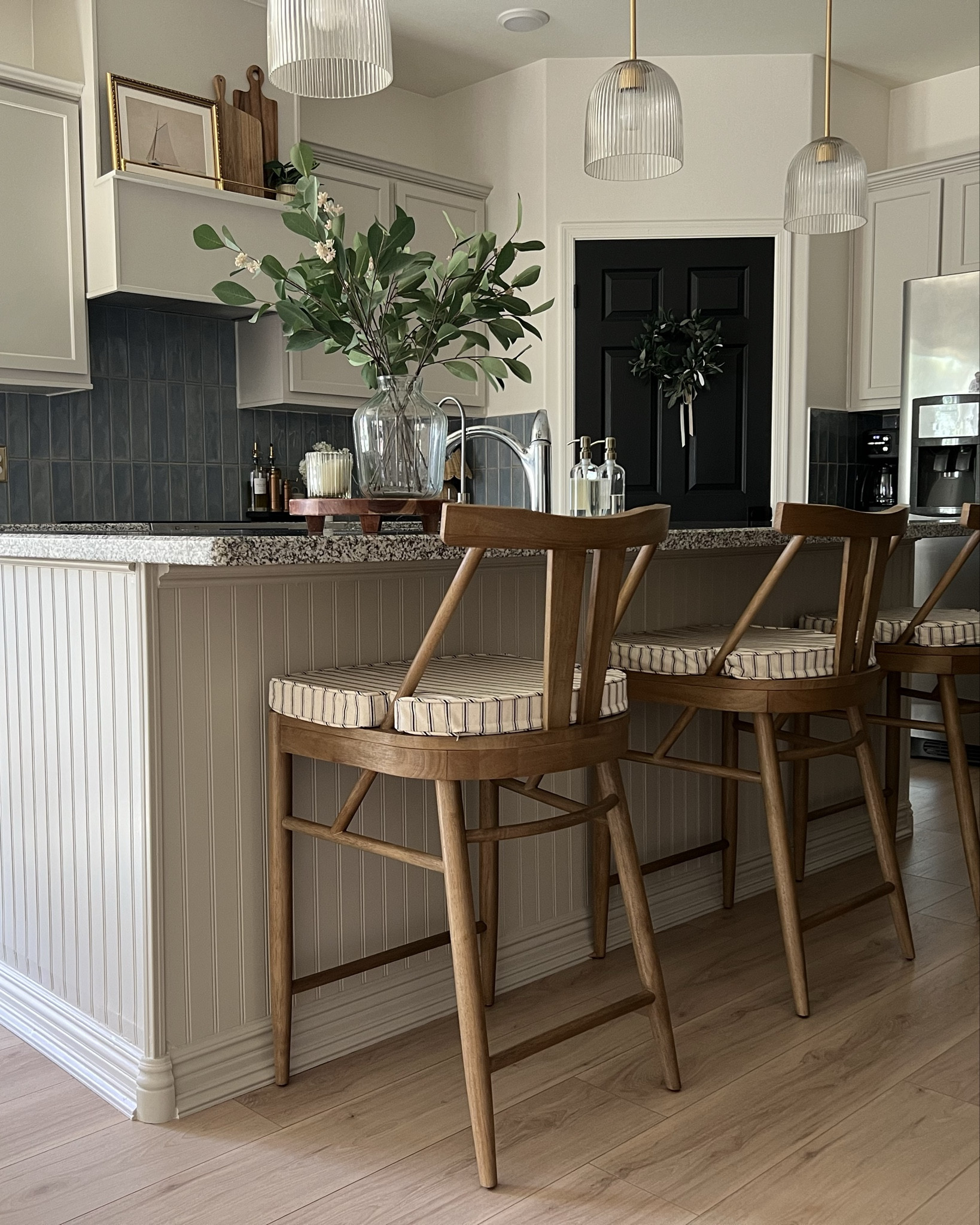 A budget friendly remodel. To keep costs down, we opted to keep the granite countertops (definitely not my favorite but they are in excellent condition) and keep the existing cabinets (again, in excellent condition) and just paint them. The color is @benjaminmoore Revere Pewter, a nice greige color that would blend with the cool toned floors and countertops but add a bit of warmth. To make the cabinets look more finish, we added plywood bottoms and trim pieces to conceal the exposed and unfinished frames. We splurged on new hardware for that WOW factor and went with a timeless unlacquered brass finish from @rejuvenation to also add some more warmth. Changed out the pendant lights for a reeded glass style to open up the lighting. Added a tile backsplash and this was my boldest design decision. Our walls are all white and as much as I would have loved a neutral backsplash, our only real option was white and I felt that it was too cold looking. The blue adds a nice pop to our otherwise very white and neutral house and went with haystack color grout to keep the warmth. I originally chose white grout and that was a huge mistake I quickly realized before it was too late. The biggest change was removing the microwave from above the stove and I built a custom range hood cover instead with a shelf with a brass railing. I love this little shelf and it add some much needed character to the kitchen. Lastly, to make the kitchen island feel more finished and less “builder-grade,” we added some leftover headboard paneling to cover the textured drywall and make the corners 90 degrees. Added some thicker and more detailed baseboards and trim pieces to give it that pop. Finished the project with these counter stools from @ballarddesigns and they are absolutely perfection! My Nancy Meyers style kitchen is complete minus some pieces for styling the counters and a new faucet. What was your favorite part of this project? ⬇️


#LTKHome