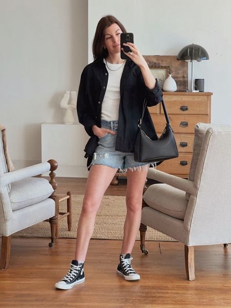 Caroline Joy of Unfancy wears a minimalist outfit featuring Converse Chuck Taylors, denim shorts, and an oversized button up shirt.