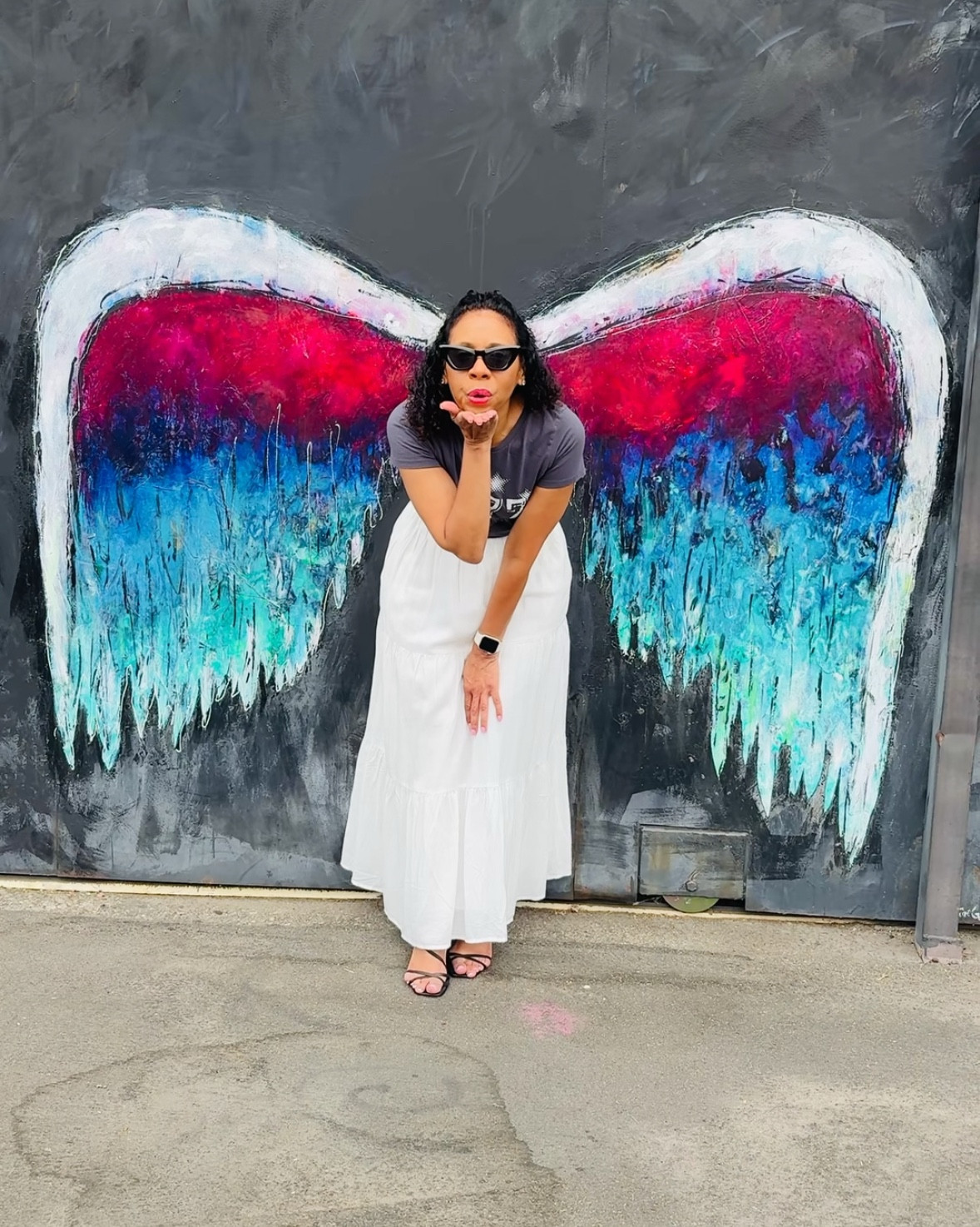 I stopped by the Arts District in downtown LA for National Be an Angel Day and couldn’t resist the angel wings mural backdrop. I styled a charcoal gray graphic tee with VICI’s Burst of Bliss Tiered Maxi Skirt in white for the perfect mix of edgy and feminine. I dressed up the look with strappy black heels and black cat-eye glasses, then balanced it all out with the long, ruffled tiers of the maxi skirt for a softer, more angelic finish. Effortless, chic, and city-photo-op ready. ✨ #ModestFashion #FeminineStyle #MaxiSkirtStyle #SummerStyle #OOTD #StreetStyle #CityChic 

#LTKStyleTip #LTKSeasonal #LTKxVICI