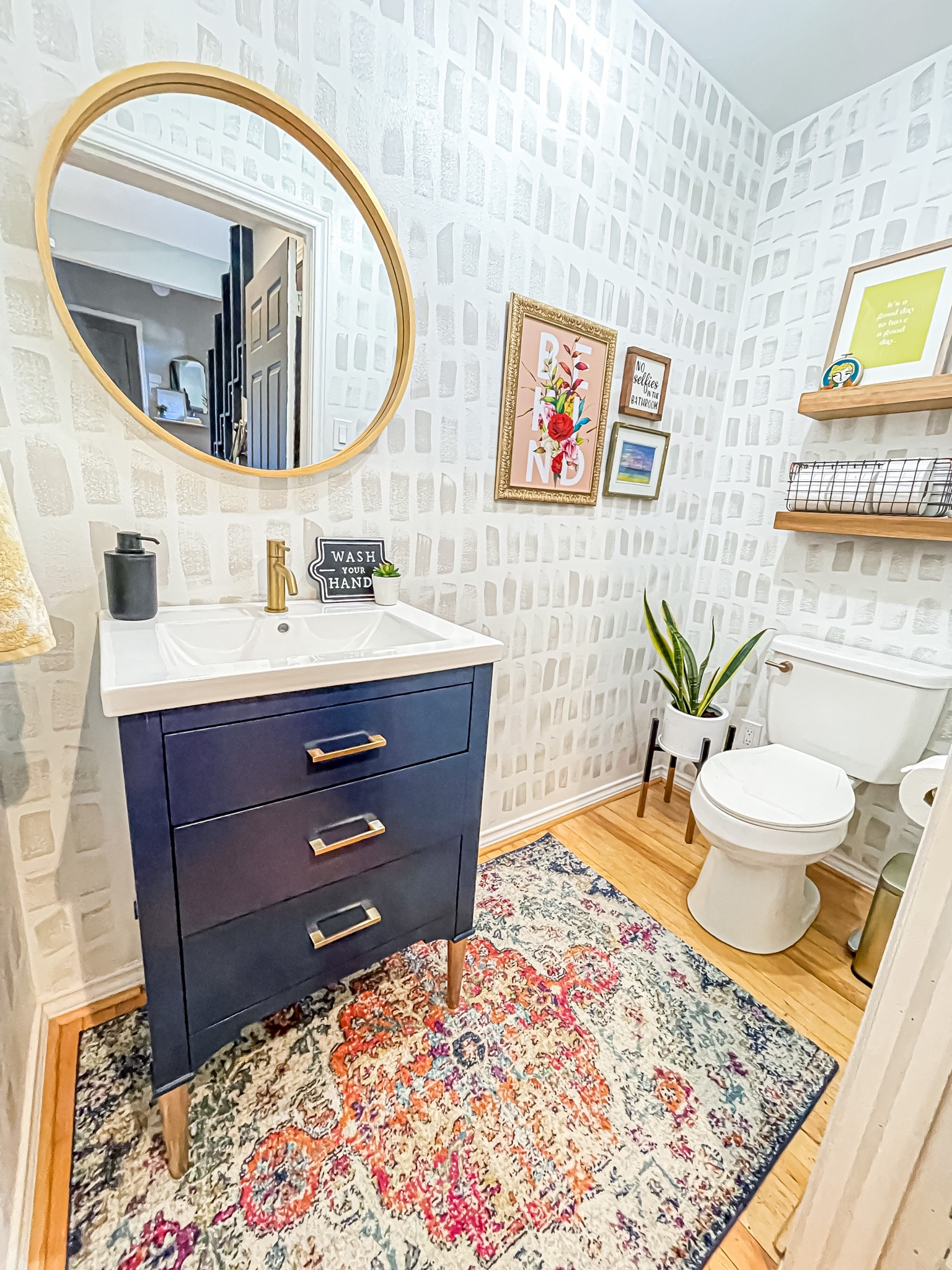 Powder room / half bath design inspiration. Hand painted wallpaper. Whimsical art. Word art. Navy vanity. Vintage rug. Plant. Floating shelves  

#LTKhome