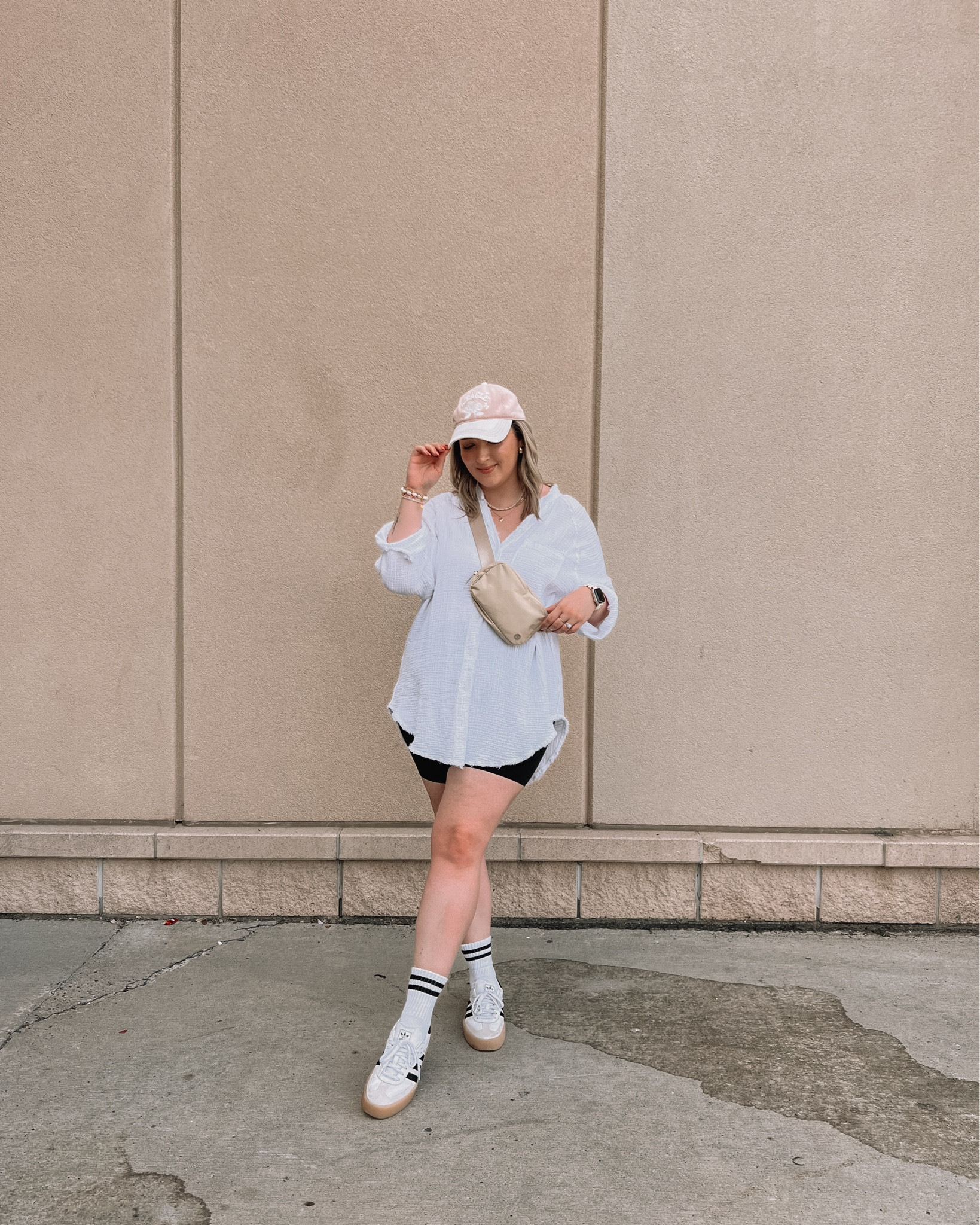 Midsize athleisure outfit - oversized button up shirt (linked this year’s version),  black biker shorts (size L), adidas sambas (size down .5), lululemon belt bag
