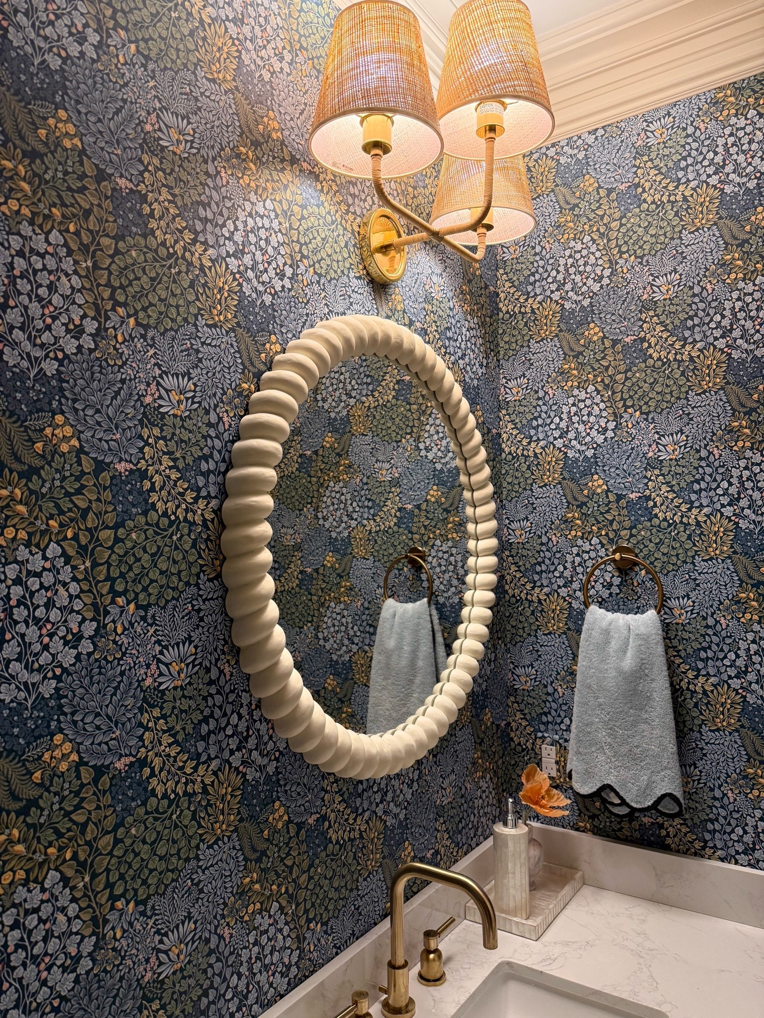 This powder room might be one of my favorite spaces in the house! The moody floral wallpaper, sculptural mirror, and woven brass sconces are such a beautiful combination. Proof that a small space is the perfect place to make a big design statement.

powder room decor, floral wallpaper, statement bathroom mirror, brass wall sconces, woven lighting, small bathroom design, moody bathroom decor, powder room inspiration, scalloped mirror, bathroom makeover, classic home decor, girlonthehudson