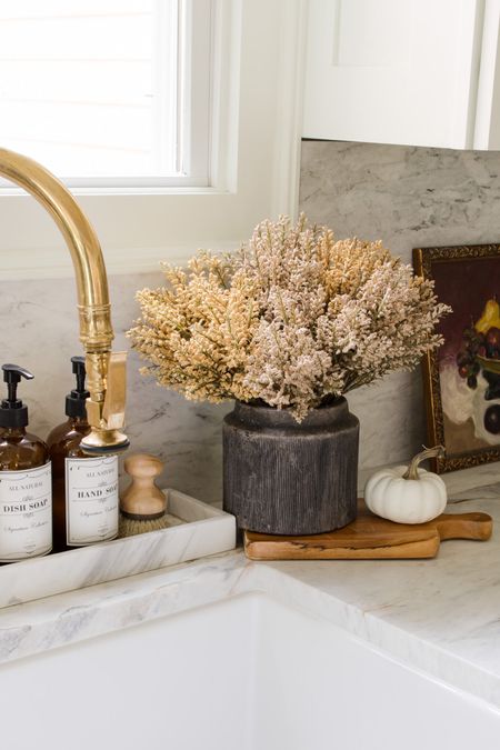 Fall decor in the kitchen. White kitchen with marble countertop. Marble tray? Amber soap bottle, fall stems, brass faucet, white pumpkin 

#LTKhome #LTKfindsunder50 #LTKSeasonal