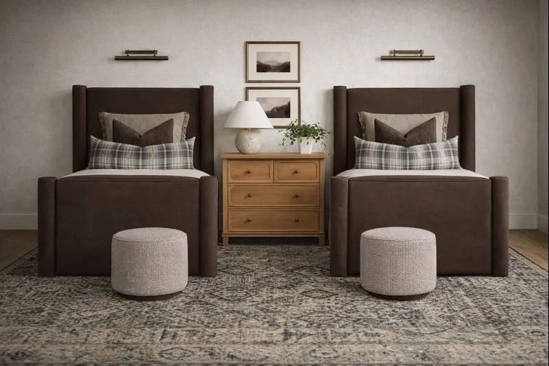 The foundation of this room is its symmetrical layout. Twin upholstered beds anchor each side of the space, creating a sense of balance that feels soothing and intentional. The substantial headboards provide a cozy, cocoon-like feel, while their deep brown tone grounds the room and adds a sense of maturity that can grow with your child.