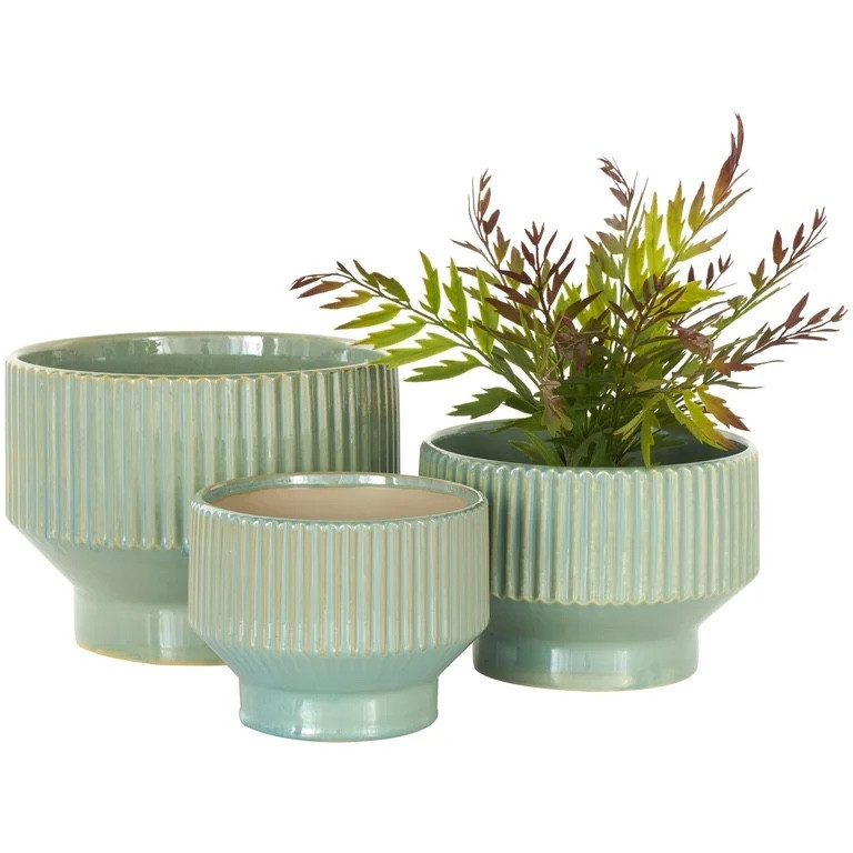 DecMode 10", 8", 7"W Wide Green Ceramic Planter with Linear Grooves and Tapered Bases (3 Count) is a unique addition to your stylish home. Elevate your greenery area as you display these ceramic planters on wooden plant stands or shelves to achieve a modern look. This item ships in 1 carton. Please note that this item is for decorative purposes only and is not food safe. Suitable for indoor and outdoor use. This item ships fully assembled in one piece. Maximum weight limit is 15 lbs. These planters have drainage holes at the base. This green colored plant pot comes as a set of 3. Modern style.

#LTKHome #LTKSeasonal #LTKStyleTip