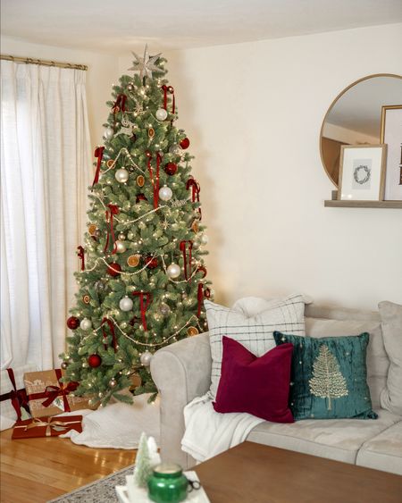Living room with a faux pre lit Christmas tree, 3 Christmas throw pillows, velvet burgundy ribbons on the tree and wrapped around the gifts, presents under the tree, burgundy ornaments, burgundy throw pillows.

#LTKhome #LTKHoliday #LTKSeasonal