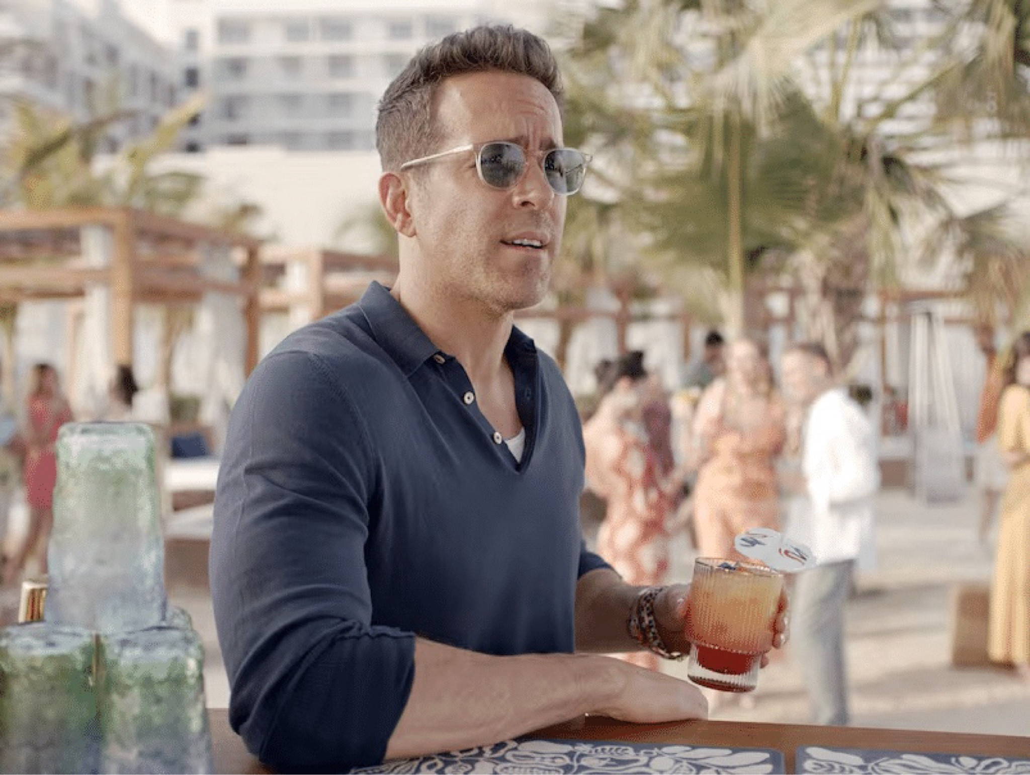 Ryan Reynolds announced as the Yas Chief Island Officer wearing a blue Boglioli polo and Oliver Peoples sunglasses