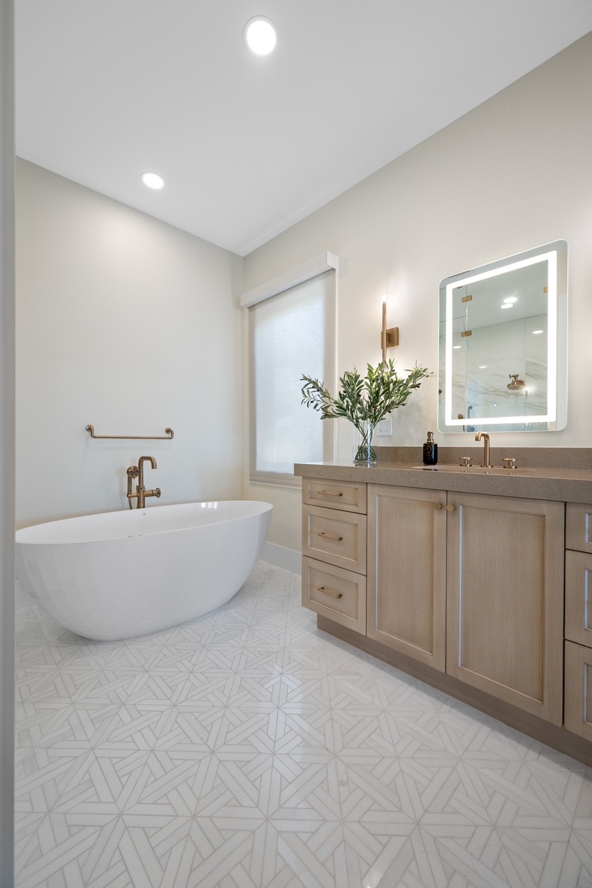 Dreaming of a spa-quality escape? 🛁✨
Transform your daily routine with this Modern Vintage primary bath. This look perfectly balances the warmth of natural wood with sleek, contemporary lines.

Shop the Look:

The Vanity: Soft white oak cabinetry paired with a clean neutral countertop creates an airy, high-end feel.

The Details: Elevate the space with Champagne Bronze hardware and a statement backlit LED mirror for that perfect glow.

The Tub: A deep freestanding soaking tub acts as the ultimate focal point for relaxation.

The Floor: Add subtle character with geometric encaustic-style tile in a soft beige and white palette.

Design Tip: Use consistent metallic finishes across your faucets, sconces, and towel bars to tie the whole room together seamlessly.

Follow my shop on the @shop.ltk app to shop this post and get more home inspo!

#LTKhome #BathroomRemodel #ModernVintage #SpaBath #HomeDesign #InteriorInspo 

 