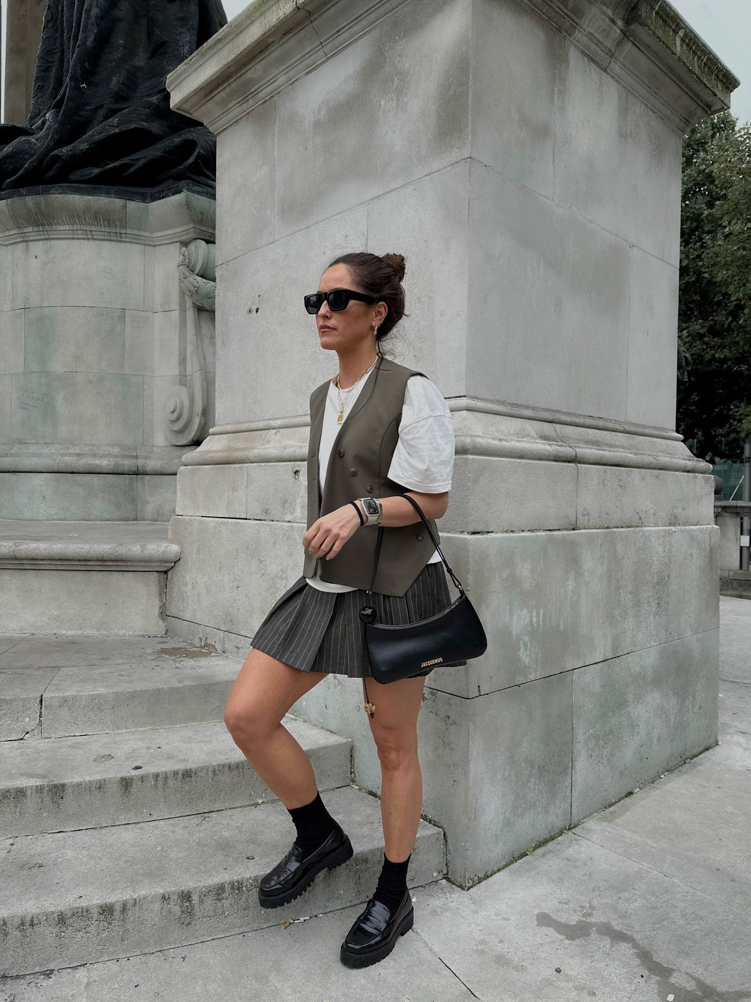 Summer Autumn transition outfit. Black loafers. Chunky loafers. Black bag. Jacquemus handbag. Shoulder bag. Waistcoat. Green waistcoat. White tshirt. Capsule wardrobe. Pleated skirt. Grey skirt

#LTKeurope #LTKitbag #LTKSeasonal