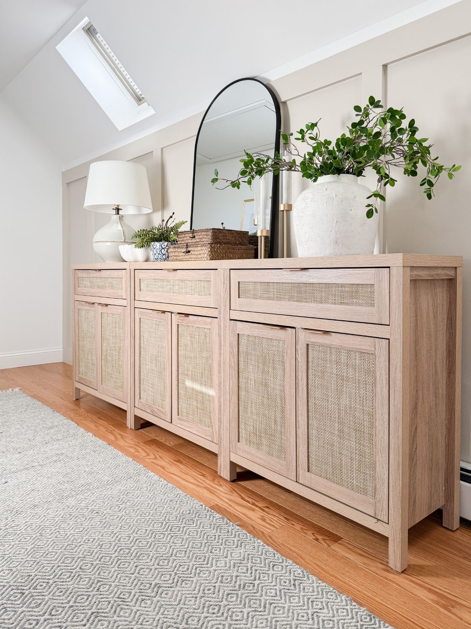 Light wood and cane sideboard styled with oversized arched mirror, ceramic vase with greenery, woven boxes, and soft neutral lamp. A timeless coastal furniture moment with layered textures. 
cane sideboard, arched mirror, sideboard styling, coastal console decor, woven boxes, neutral lamp, greenery stems, coastal living room, entryway console, light wood furniture, layered textures, modern coastal decor, sherri calnan home

#LTKHome #LTKSeasonal